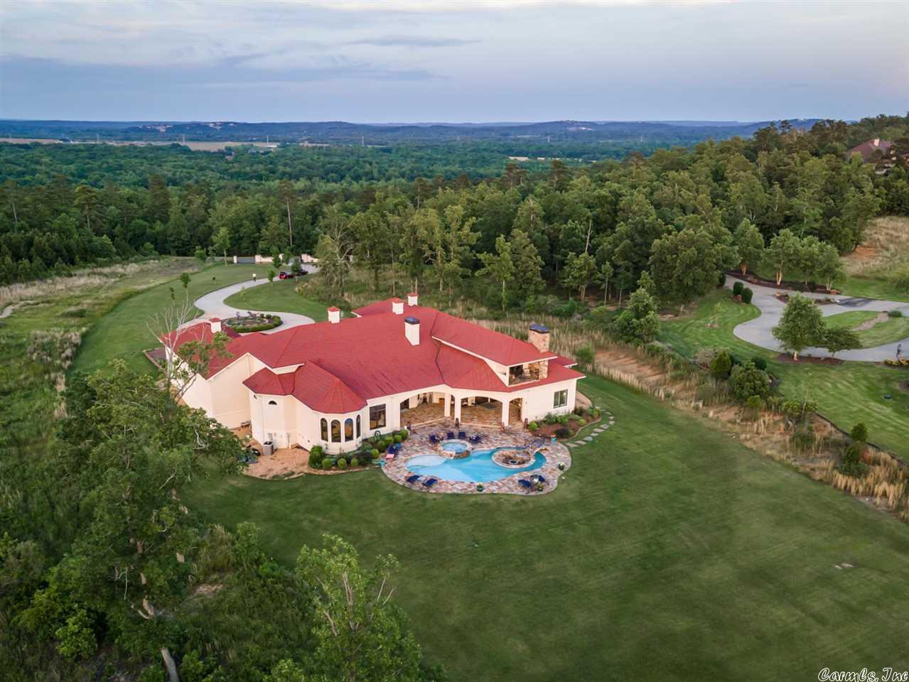 Transport yourself to a Mediterranean Estate overlooking Lake Maumelle. On more than four acres, this serene villa is made for entertaining! A formal entry opens to a dining room with seating for twelve as well as a music room with a double-sided fireplace adjoining the hearthroom.The gorgeous stucco one-level overlooks the flagstone patio & pool.The patio features an outdoor kitchen, pizza oven, fireplace & entertainment area while a hot tub flanks the gunite, salt water pool. 8 garage bays. See remarks.