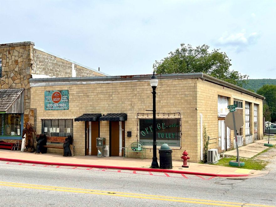 MIXED USE/ PRICED TO SELL QUICKLY  -  with private parking. Prime corner location with Main Street frontage just steps from the Stone County Courthouse Square. Variance from city permits upstairs short-term rental AKA " the garage apartment" included in the listed square footage. All new: commercial plumbing, electrical, HVAC, oversized skylights, roof insulation and sound dampening.  Features include 2 offices ( income producing), a garage apartment, 4 ADA bathrooms - rough plumbed,  main bay garage which could easily be converted to 3 retail units, Tesla level 2 EV charger with an adaptor for general EV use,  and approximately 10-20 parking places.  Expansion to building and private courtyard next door possible. Video walk-thru link available on request.  Buyer to finish out to suit- most major renovations completed.  Ideal for restaurant, music venue or multi bay retail or offices or a combination of any of the above.