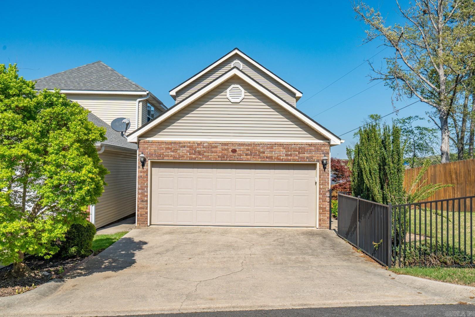 This enchanting townhome is located in the charming gated enclave of "Majestic Lake Village," situated along the shores of Lake Hamilton. End unit placement offers a fully fenced side yard, perfect for privacy and pets. Pull into your 2-car garage to enter this freestanding townhome (you own the land on which it sits!). The walk-in level hosts open-concept kitchen / dining / living spaces featuring high-style interior finishes including: hickory wood flooring, quartzite countertops + backsplash, stainless appliances, gas cooking + fireplace, new cabinets, and updated fixtures. Upstairs, both bedrooms are accompanied by en-suite bathrooms, with the master suite offering direct balcony access. Enjoy stunning water and mountain vistas from one of two covered balconies. Majestic Lake Village's POA dues of $100 per month are some of the most conservative in Hot Springs. Enjoy all that gated Majestic Lake Village has to offer, including fishing off of the boardwalk, playing catch at the waterfront, or swimming off the dock. To maintain the community's charm, nightly rentals are not permitted. This residence is truly a splendid place to call your own!