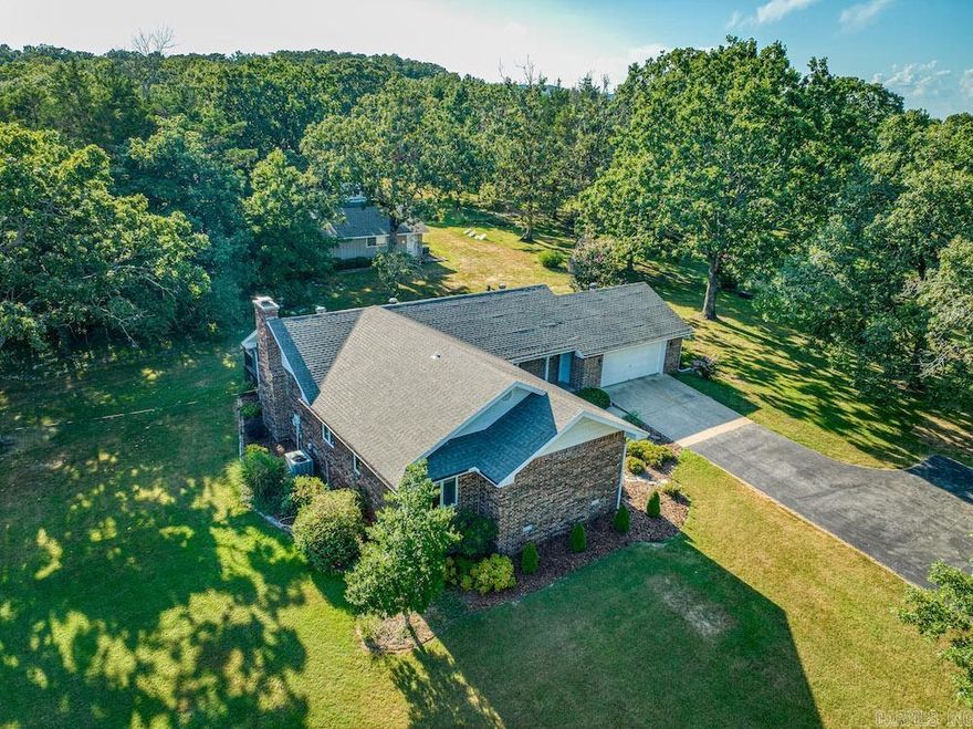 This exceptional brick home combines elegance, privacy, and convenience, just minutes from town with paved road access. Set on a park-like paradise, the property features phenomenal landscaping with hardy, low-maintenance plants, massive mature oaks, a pond, garden, and winding UTV trails. The single-level home is designed for comfort, boasting a recently remodeled kitchen with custom cabinetry, granite counters, a large island, stainless steel appliances, a double oven, Wi-Fi refrigerator, and spacious pantry. The dining area flows into the vaulted living room with floor-to-ceiling brick fireplace and glass sliders leading to a partially covered back deck overlooking the pristine grounds. The master suite offers dual closets and full ensuite, while two guest bedrooms and a large bathroom provide comfort for family or guests. Additional highlights include a 2-car garage with storage, large laundry with sink and half bath, neutral tones, custom woodwork, and abundant natural light. A heated/cooled metal shop and separate machine shed offer ideal space for vehicles, RVs, equipment, or hobbies. With wildlife, trails, and serene scenery, this rare estate is truly remarkable.
