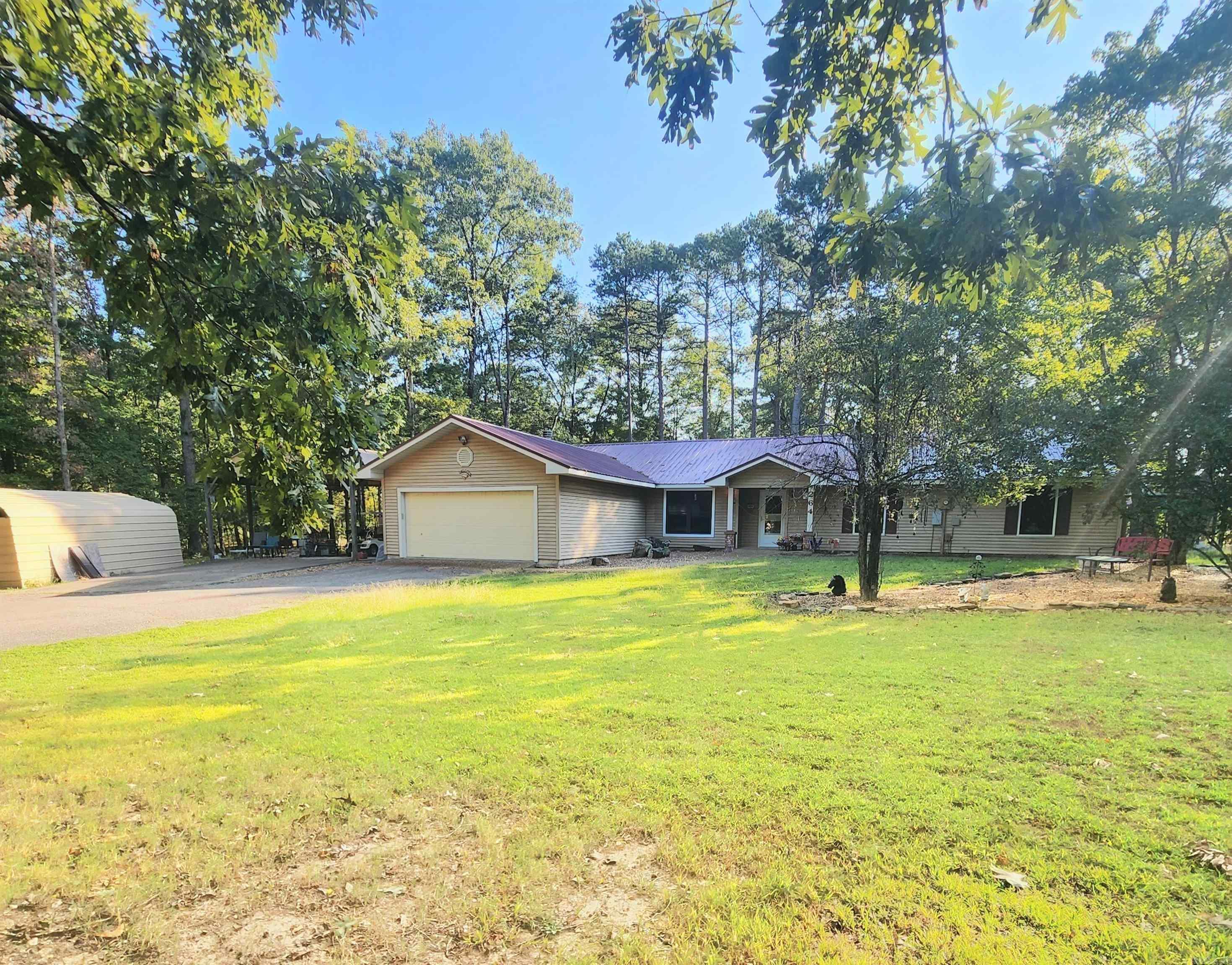 Welcome to the market! Furnished home situated at the end of a quiet dead-end street, this beautiful 4-bedroom, 2.5-bathroom home offers a country setting just minutes from the Old Highway 25 boat launch. Surrounded by mature trees, you'll enjoy privacy on this spacious 1.26-acre lot with no restrictions. This home features a new roof (installed February 2025) and a washer and dryer approximately 3 years old. Step inside and enjoy the open, inviting spaces – with a living room and a cozy den with a fireplace for those chilly evenings. For added comfort, one of the bedrooms could be a guest suite as it comes complete with a half bath – ideal for visitors or extra privacy. Enjoy the outdoors from your spacious back deck great for relaxing in the fresh air. Outdoor enthusiasts will appreciate the greenhouse, metal two-car carport, and additional metal storage building, offering plenty of space for hobbies, gardening, boat storage and storing your tools and equipment.