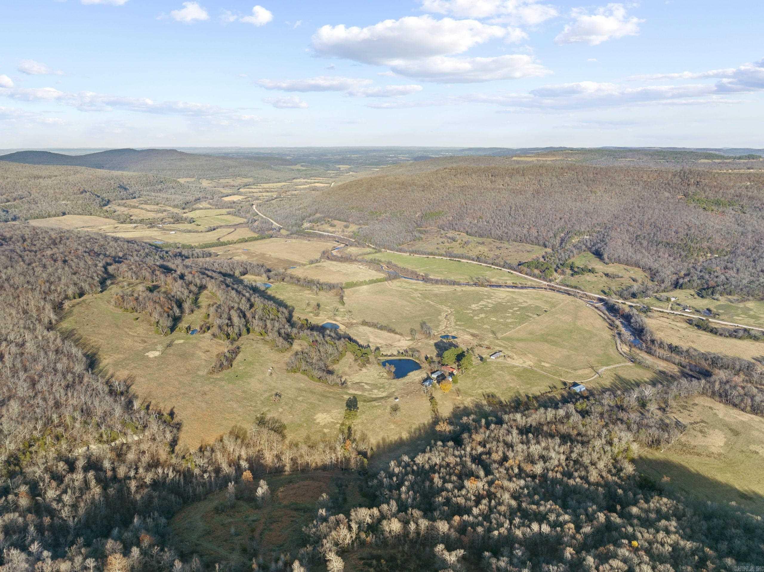 What an unbelievably rare and special tract on the famous Bear Creek. This stunning farm is loaded with features you just canāt duplicate and has something to offer any buyer. Tucked in the majestic valleys of this stretch of the Ozark Mountains is a rolling ranch with fantastic diversity. The massive and beautiful Bear Creek is flowing for over ¾ mile through the property. This year-round creek is known for its recreational perks; just imagine cooling off in the swimming holes on a hot summer day, hooking a smallmouth bass on a cool spring morning, sitting by the waterfalls listening to the soothing sound only running water can make, or even watching massive bull elk getting a drink on an early fall afternoon. Conveniently located on Hwy 27 South, the access is very easy and just a few miles from the community of Marshall, AR. The newly constructed masterpiece true log cabin is on one side of the road. This marvel is full of custom features like granite countertops, vaulted ceilings, custom alder doors, a towering freestanding dual-sided rock fireplace, an oversized covered wrap-around deck, custom hickory hardwood flooring, real wood blinds, and much more.