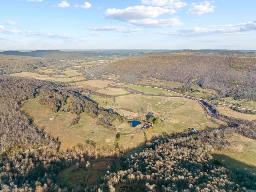 What an unbelievably rare and special tract on the famous Bear Creek. This stunning farm is loaded with features you just can’t duplicate and has something to offer any buyer. Tucked in the majestic valleys of this stretch of the Ozark Mountains is a rolling ranch with fantastic diversity. The massive and beautiful Bear Creek is flowing for over ¾ mile through the property. This year-round creek is known for its recreational perks; just imagine cooling off in the swimming holes on a hot summer day, hooking a smallmouth bass on a cool spring morning, sitting by the waterfalls listening to the soothing sound only running water can make, or even watching massive bull elk getting a drink on an early fall afternoon. Conveniently located on Hwy 27 South, the access is very easy and just a few miles from the community of Marshall, AR. The newly constructed masterpiece true log cabin is on one side of the road. This marvel is full of custom features like granite countertops, vaulted ceilings, custom alder doors, a towering freestanding dual-sided rock fireplace, an oversized covered wrap-around deck, custom hickory hardwood flooring, real wood blinds, and much more.