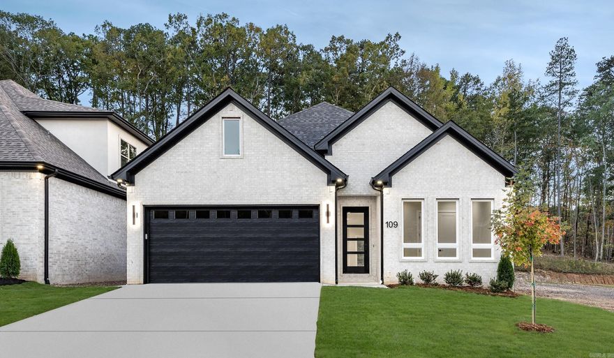 Welcome to 109 Kinley Loop, a stunning home where modern style & comfort come together beautifully. With its sleek black front & garage doors, designer finishes, and an open, light-filled layout, this home stands out from the rest.  Step inside to a spacious entryway with a statement light fixture & light wood floors that flow throughout the main living spaces. The open floor plan connects a stylish kitchen, dining area, & living room anchored by a fireplace & huge windows that flood the home with natural light. Oversized glass sliding doors lead to outdoor living space & offer a seamless connection to the peaceful surroundings.  The kitchen is both beautiful & functional, featuring a gas stove, modern cabinetry, & plenty of room to gather and entertain. The primary suite is a true retreat with gorgeous views, a spa-like bathroom boasting large windows, a soaker tub, & a glass-enclosed shower. With the primary bedroom & two additional bedrooms on the main level, & a fourth bedroom with a full bath upstairs, the layout offers flexibility for guests or a home office.  Every detail in this home is designed for elevated living—modern lines, warm materials, & bright, open spaces.