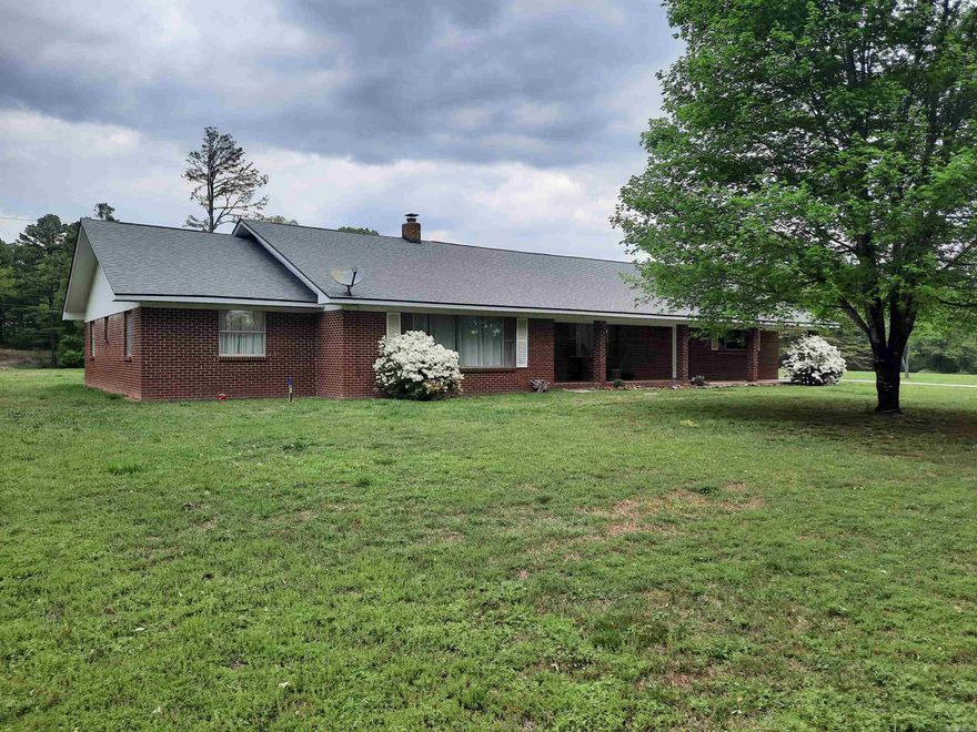 Enjoy country living just minutes from town.  This brick beauty offers a serene setting on almost 5 acres, land is level which is not easy to find here, property is the perfect mixture of cleared land and trees, with mature shade trees lining the country driveway. Home is very spacious with 3 bedrooms and 2 baths, open concept in living, dining and kitchen area. The cook of the home will love the kitchen with lots of cabinets and counter space. Nice front porch and large back porch/patio to set and relax. Over sized attached garage and detached shop/garage. This home has so much to offer, it's the perfect place to call home!