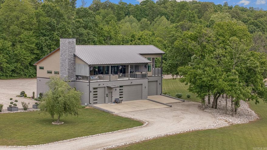 Experience this stunning waterfront river home situated on nearly 3 gated acres along premier trout waters on the Spring River. Designed for fishing, relaxation, recreation, and entertaining, this thoughtfully designed property blends modern architecture with exceptional outdoor living in a peaceful natural setting. The main residence offers 3 bedrooms and 4 bathrooms, including a spacious bunk room with six queen beds, ideal for hosting family and guests. Expansive windows and premium finishes create a warm yet sophisticated atmosphere, while an elevator provides convenient access between levels. Enjoy over 1,100 sq. ft. of outdoor living space featuring three TVs, property-wide Sonos sound, an outdoor kitchen, dining area, gas firepit, and porch swing bed overlooking the river. Additional features include an outdoor shower off the master bath, riverside firepit and lounge areas, private boat launch, tornado shelter/safe room, 3500 sq ft multi-bay drive-through garage, three full RV hookups, high-speed fiber internet, automatic backup generator, and buried 1,000-gallon propane system.