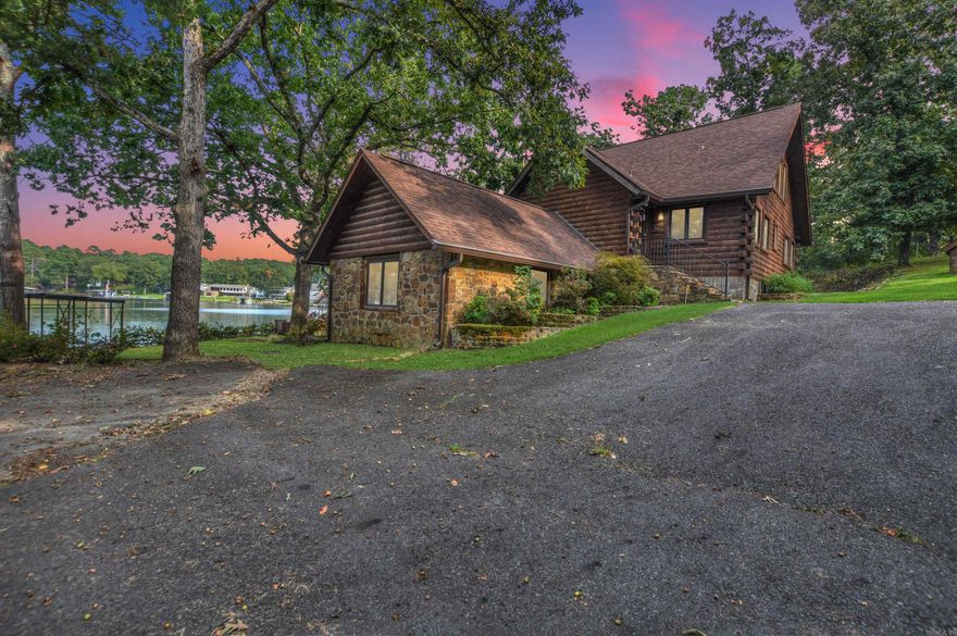 Lake Hamilton waterfront retreat! This 3,264 sq. ft., 3-story log cabin offers 149’ of shoreline with stone seawall, private boat ramp, covered double boat dock, and separate swim dock. Built in 2002 on a 1.8-acre treed lot with circle drive and detached workshop, it’s ideal as a primary residence, getaway, or nightly rental (no restrictions). The walk-out lower level features a game room, family room, kitchenette, bedroom, bath & laundry. Main level has 2 bedrooms, bath, open kitchen, family room with cozy stove, and walls of glass opening to an expansive deck. Upper level offers a private suite with bedroom, bath, and dual walk-in closets. Hardwood & tile floors plus walls of glass throughout. Proven rental history—move-in ready for lake living or investment!