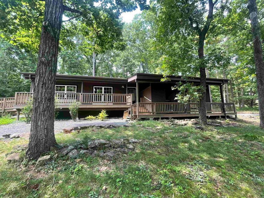 What a unique property on a large, corner lot (3 lots replatted into 1) in the heart of Fairfield Bay. Tucked back up in the trees, the only home on the street, you'll feel secluded in your own weekend getaway or full-time home. All electric. Wired for a generator. New cabinets with pullout drawers, appliances, composite countertops with shark nose edge, tile backsplash, remodeled bathroom. Refrigerator, washer, and dryer stay. Living room has a woodburning fireplace with vents that circulate heat throughout the home. A golf cart ride away from the Indian Hills golf course and The Little Red restaurant. Features a raised bed greenhouse, large deck perfect for entertaining or enjoying a quiet cup of coffee while watching the wildlife, a gazebo, and a 14x24 heated and cooled shed that could be a workshop, craft room, bunk house, guest house. Has a full loft great for storage, and a large, covered porch on the front. This home is on septic so dues are only $113 a month. Come and enjoy all Fairfield Bay has to offer.