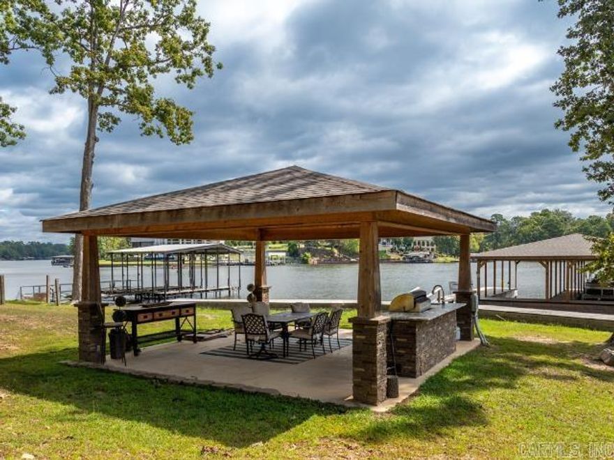 Looking for the perfect lakefront getaway and solid investment?  With 100 feet of Lake Hamilton frontage and a new 2-stall covered stationary boat dock, this home has everything you need for fun on the water and the fabulous outdoor kitchen offers the perfect setup for lakeside gatherings.    Inside there’s room for everyone with 4 bedrooms (each with lake view),  2.5 baths and a bonus/bunk room that could easily be converted to a game room.  Plus, the detached garage has been converted into additional living space that sleeps 6 with a kitchenette and full bath – perfect for additional guests or a private retreat.   Currently used as a short-term rental and offered fully furnished, this property is already set up to generate income while providing you the perfect spot for your own vacation days.  Whether you’re looking to invest or simply enjoy lake living, this one is a win-win! The adjacent lot with 98ft of lake frontage is also available for purchase and already has a boat dock.