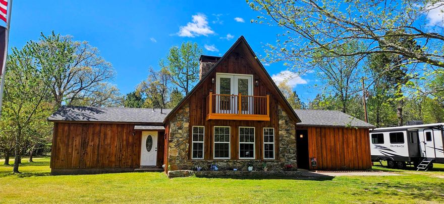 Welcome to your rustic retreat! NEW ARCHITECTURAL ROOF AND WINDOWS 2024! A 22kw auto-on Generac generator.  This charming home boasts 3 bedrooms, 1.5 baths, plus an upstairs loft with balcony. The kitchen features a huge concrete island with copper sink, concrete countertops, surface range, and wall oven.  Vaulted ceiling in the living room with a striking wood-burning rock fireplace accentuated by a cedar mantle. Stamped concrete floors, antler chandelier, wood walls and ceiling. Custom fixtures throughout. Barn doors in the bedrooms. Off the living room is a large covered deck. A spacious 40x50 shop complete with electric, HVAC, 2 bay doors and plumbed for bathroom.  An additional storage building. All nestled on approximately 1.5 acres. Don't miss this opportunity to own this one of a kind property. Air compressor on back of shop does not convey.