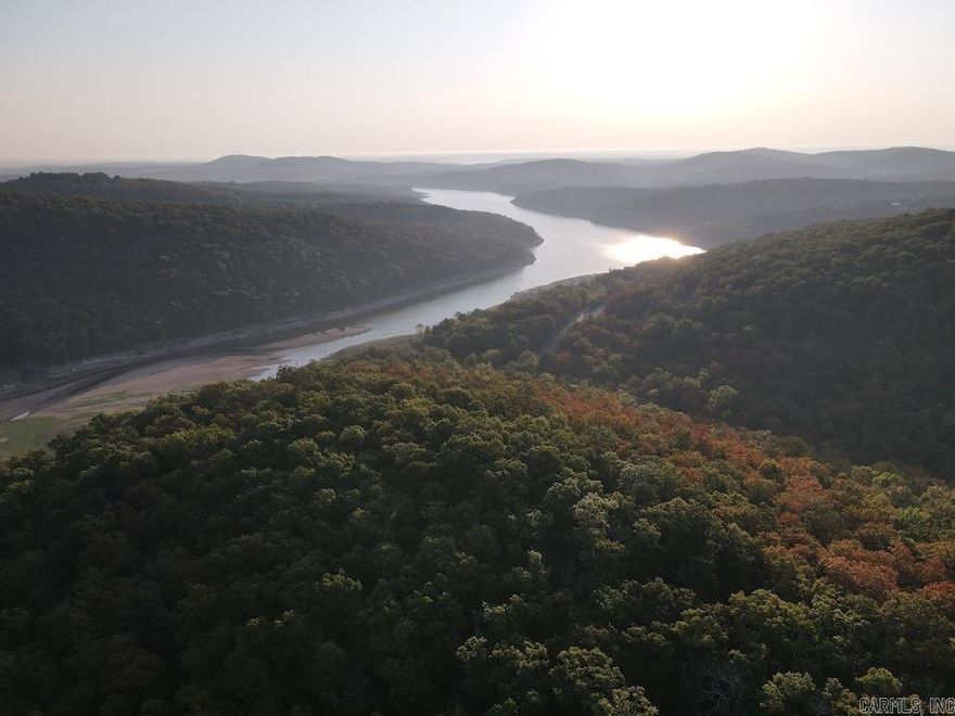 Nestled in the rolling hills of Marion County, this property borders Bull Shoals Lake and offers the perfect blend of privacy, recreation, and natural beauty. With paved road access, a gated entrance, and a quality internal road, it immediately feels inviting and secure. Mature white oak, hardwoods, and pine create valuable timber and ideal wildlife habitat, while the ridge tops and expansive timber provide excellent hunting stand locations. At the center lies a large clearing with a custom-built platform stand, perfect for food plots and hunting, surrounded by cedar thickets offering prime deer and turkey cover. A small metal shed adds storage for equipment, blending practicality with beauty. Less than half a mile from Moccasin Creek Public Access, the property grants immediate access to world-class fishing, boating, and water recreation, with the renowned White River nearby. With potential for stunning lake views from the eastern ridge, this tract is ideal for hunting, a cabin site, or a private retreat by the water.