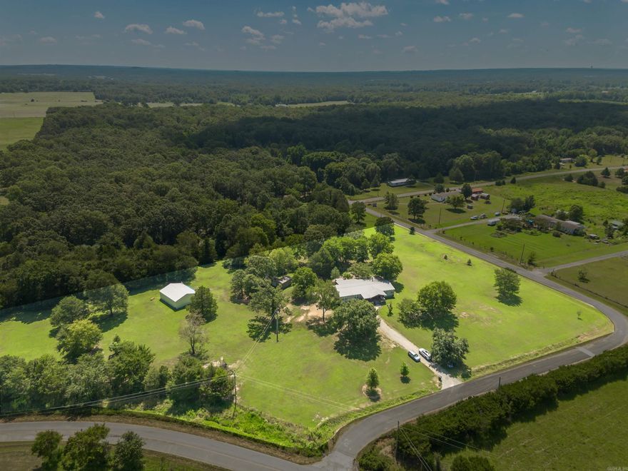 Beautiful country style home is situated on 5 acres of beautifully landscaped land and 3,000 sq ft of heated and cooled living space. Relax on the huge front porch with porch swings, french doors as you watch the sun set. The home features a metal roof that provides a wonderfully calming sound when it rains, and public water is available for your convenience. For gardening enthusiasts, there is a well and pump on the property too. Large windows throughout the home allow natural sunlight & creating a warm and inviting atmosphere. Inside, is a spacious living room with a cozy wood fireplace, a perfect place to gather with friends and family. The kitchen is a chef's dream, with plenty of counterspace, a custom antique island, and a gas range with 5 burners. A separate pantry provides ample storage for all of your cooking essentials. Outside the living room you will step into the sunroom and be amazed by the stunning views of from the windows. Watch animals and nature in this 300-sq ft sunroom is fully heated and cooled, making it the perfect place to relax and enjoy. Large covered back porch, tiered pad - grilling, firepit, & 30x40 shop. Property is listed Under Appraisal Value $323k