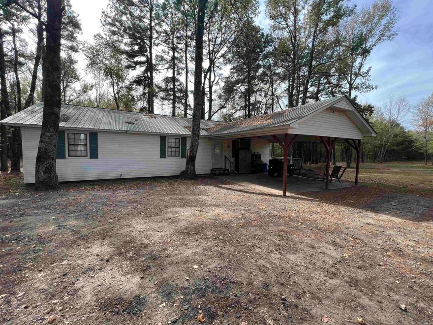 This home has updates and  is situated in a country setting at the end of a private road. The interior offers an open-concept floor plan with a vaulted ceiling, new flooring throughout, and a spacious laundry room. The kitchen features stunning butcher block countertops, ample cabinet space, and a movable workspace island. The outdoor amenities include a wooden deck, carport, fenced-in area suitable for pets, as well as a sizable front and back yard. A small shop, complete with water and electricity, including one 30 and one 50-amp plug for an RV, is also available on the property.