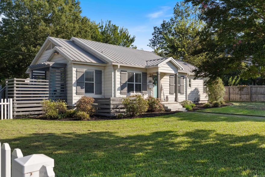 Have you been looking for your white picket fence American Dream home? This Old Town stunner is it! Situated on a beautiful corner lot, this home exudes character. The home features hardwood floors with custom inlays. A beautiful fireplace serves as the focal point of the living room.  The dining area has plenty of space for a large table and is open to the living room. In the kitchen you'll find concrete countertops, a subway tile backsplash, a stainless steel refrigerator that conveys with the home, and chevron pattern tile floors. There's a breakfast nook just off the kitchen that can double as an office. Hardwoods in the bedrooms. The primary ensuite bathroom features a gorgeous custom tile shower. There's a private deck off of the primary suite as well as a large deck off the side of the laundry room, which is also very spacious. The roof is metal, which could help save costs on insurance. There's a chicken coop in a fenced-in area. The larger coop conveys! You will also be able to store your lawn equipment in the outdoor storage building. Great location right next to Conway Junior High. Close to Hendrix, Conway High, and downtown Conway. Agents, see remarks.