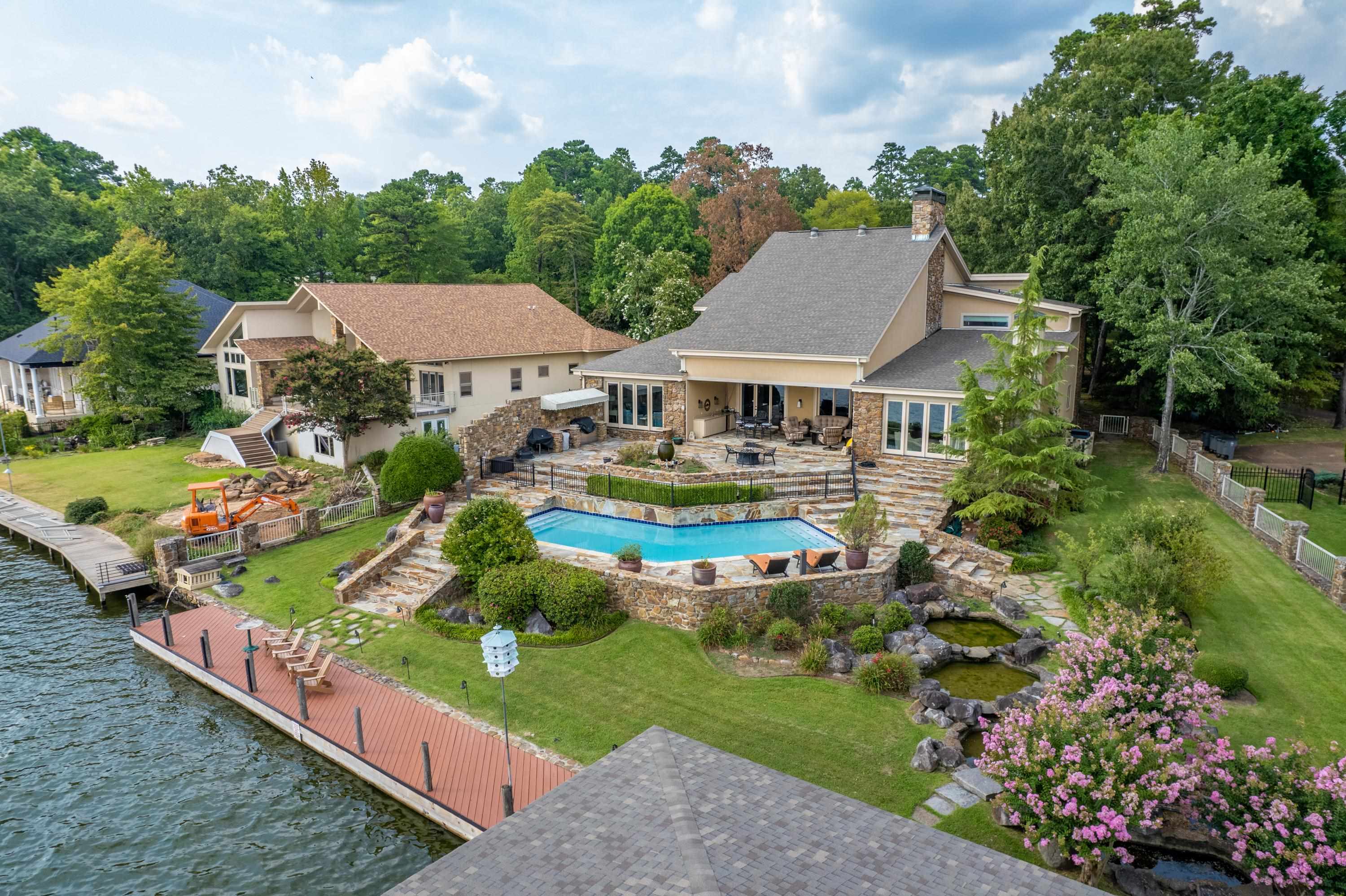 Must see this beautiful lakeside retreat on the main body of Lake Hamilton. This stunning 5 Bedroom 5.5 Bath home features breathtaking views throughout and the interior includes spacious living room, with a massive 40' tall fireplace, multiple living areas, luxurious master suite with sitting room and fireplace, a huge foyer, wetbar and more! The exterior features a beautiful pool, outdoor kitchen, firepit, updated boardwalk and two stall covered boat dock, green space to enjoy, and much more.