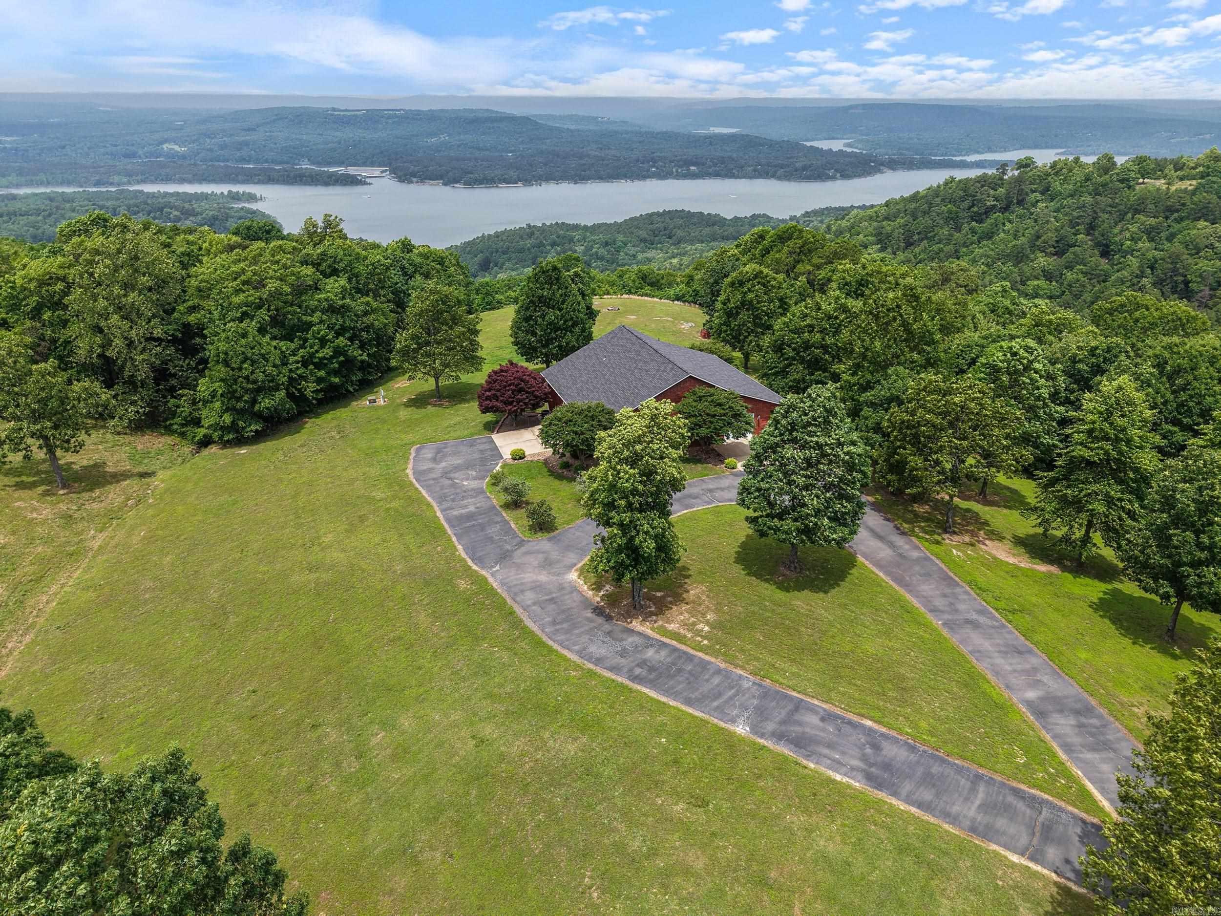 Imagine seeing this breathtaking, panoramic view of Greers Ferry Lake from your very own home on a hilltop point! Every detail of this one-owner home was immaculately planned, and much of it was updated in 2024. As you drive in, there is a 1,500sqft fully insulated garage/shop combo attached to the home. Each story in the home has the ability to be used by a separate group of guests. The main floor of the home features a spacious kitchen, full bath, and a bedroom and living room that both have spectacular views from the windows. The walk-out basement is constructed of insulated concrete (ICF), making it the ultimate safe room, complete with its own living area, bedroom, full bath, and mechanical/storage room. Additional features include quartz countertops, Pella casement windows, and luxury vinyl floors. Want something bigger? Use this home until you build your dream home and you'll have an amazing guest home, as the original owners intended. There is plenty of room on the 13.5 acres, which includes a waterfall you can hear from the porch during wet weather! There is also an additional 25 acres across the road, much of which also has a fantastic view.
