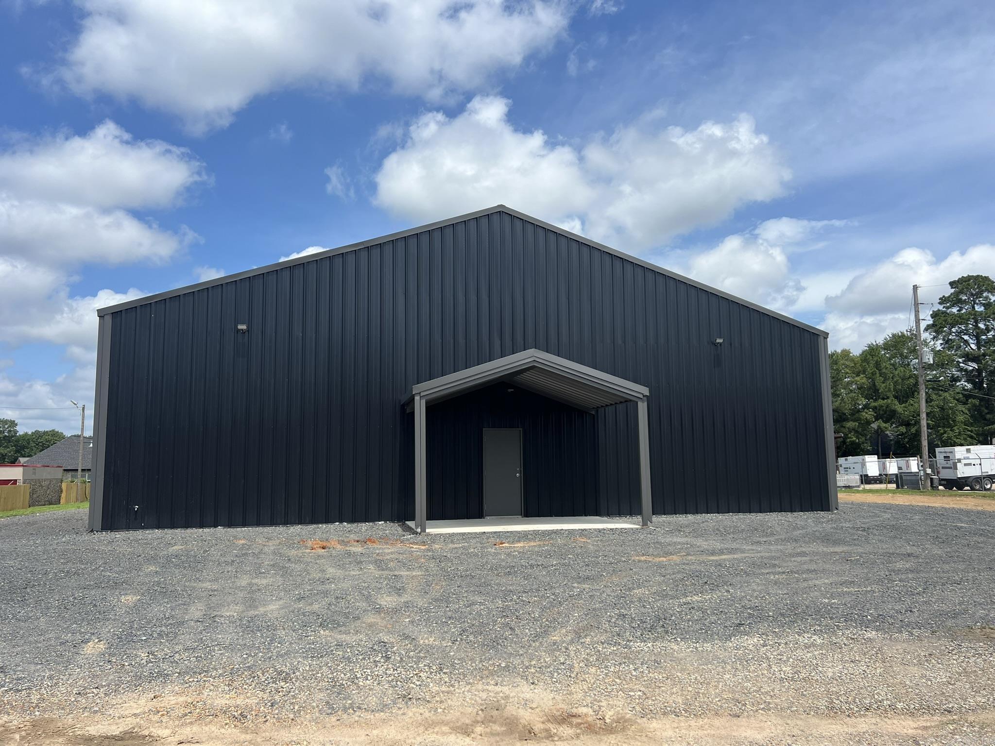 Brand new 60 X 80 METAL BUILDING w/ 60 x 20 awning on the back. Side walls are 15', center of rooms are 20'+ high. There is a center wall dividing the building into 2 separate sections. Double doors between the sections can be left opened or locked off for separate businesses. Each side has a 1/2 bath. The front side has an office space with floored storage above & a full staircase to the upstairs. Front office will have a mini-split unit for AC & Heat. Completely fenced w/ ornamental iron fence on the front & iron gate @entrance. There is a little finishing to do inside, bath rooms are not complete. They will have both have vanities & toilets. Tax figure is based on unimproved land since the building is brand new.Explanation for some Features: (S) Reason for selling: Built it to sell; (ZC) Wall type: Metal; (ZD) Sq footage source: Builder. Owner of the LLC is a licensed Realtor in Arkansas.