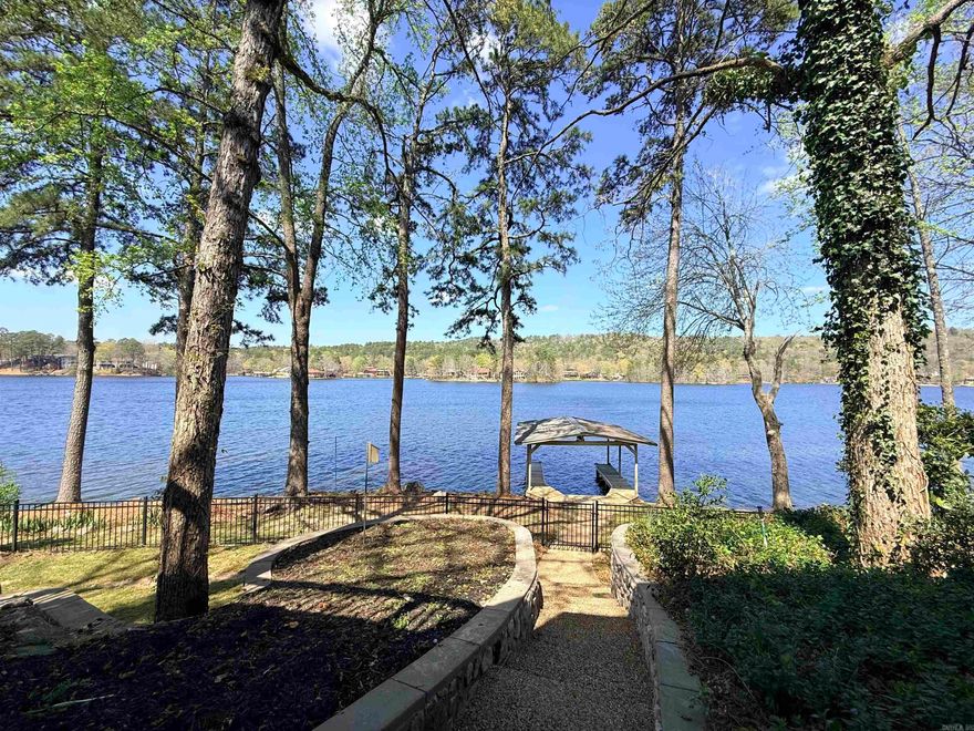 Lakefront opportunity on Lake Desoto—a premier ski lake—featuring over 100 feet of shoreline, private boat dock, and breathtaking open water views! Ideal for a vacation home, short-term rental investment, or peaceful retirement retreat.  Architecturally appealing inside and out, this spacious home offers 3 bedrooms, 3 baths, 2 living areas, a loft, and 2 bonus spaces plus a workshop/craft room for ultimate flexibility. The main level features a primary suite, expansive bonus room, and stunning lake views from the kitchen and living area. The lower level includes 2 bedrooms, full bath, and second living area—perfect for guests or multi-generational living.  Enjoy two large decks overlooking the water, ideal for entertaining or relaxing. Fenced backyard with rod iron fencing, 2-car garage, and circle drive add convenience. Located in amenity-rich Hot Springs Village with lakes, golf, and trails—this is lake living with strong investment potential!