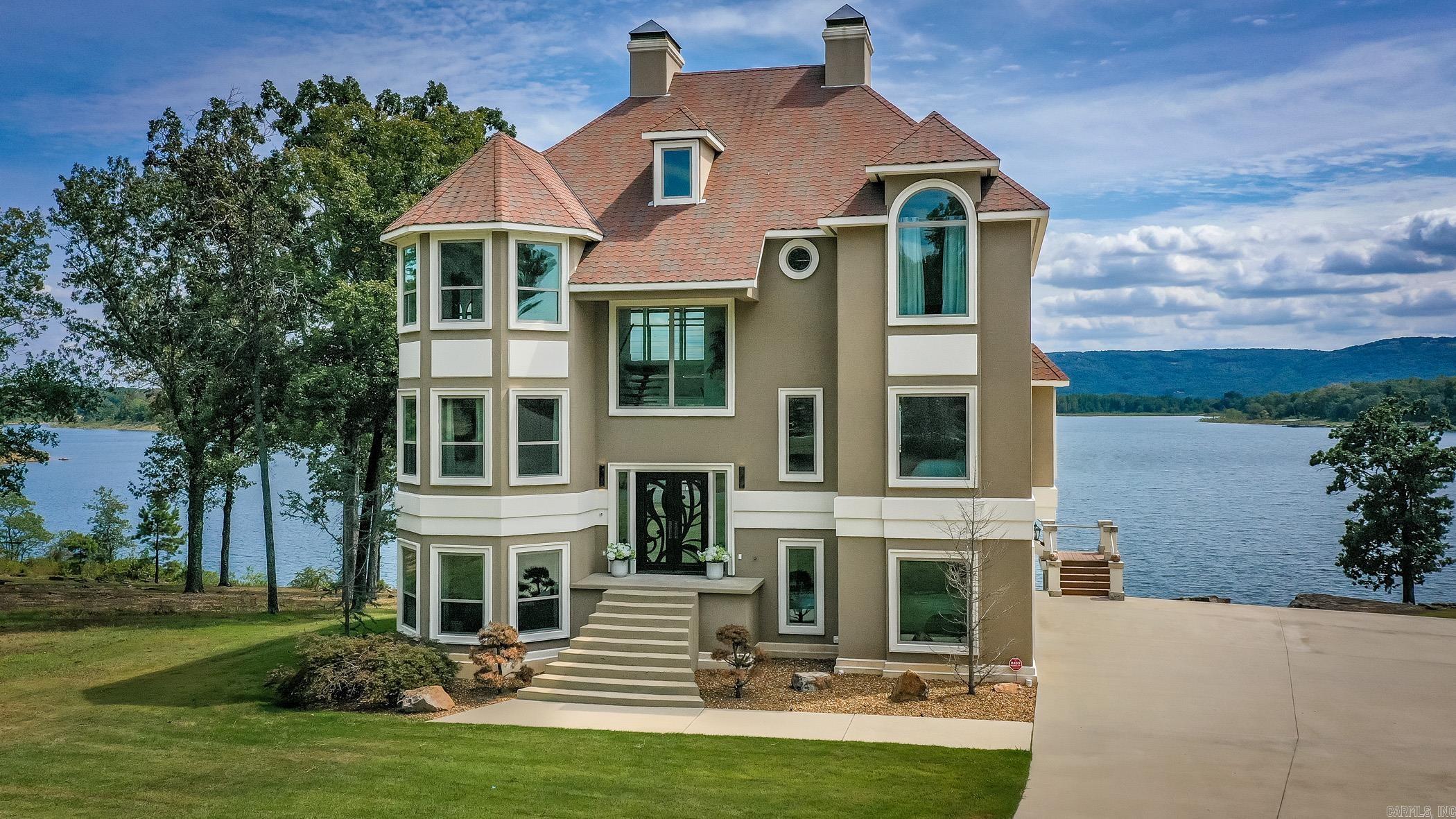 LAKEFRONT AND LAKEVIEW LUXURY LIKE NO OTHER - Prepare to be captivated by this extraordinary lakefront residence where architectural artistry meets the serene beauty of nature. Perfectly perched to maximize panoramic views, this home offers an unmatched blend of privacy, elegance, and front-row access to the water. From the moment you arrive, you're greeted by an endless blue horizon. Inside, walls of glass invite the lake in, flooding open concept living spaces with natural light and offering uninterrupted vistas. High-end finishes, soaring ceilings, and designer details create a sophisticated yet welcoming ambiance. Step outside to your private balcony on all three levels. Ideal for morning coffee, sunset dinners, or launching your kayak for a morning or afternoon on the water. Whether you're hosting guests or savoring a quiet retreat, this home offers spaces designed for connection and tranquility. This is not just a home--it's a lifestyle. A rare opportunity to own lakefront luxury that truly stands apart.