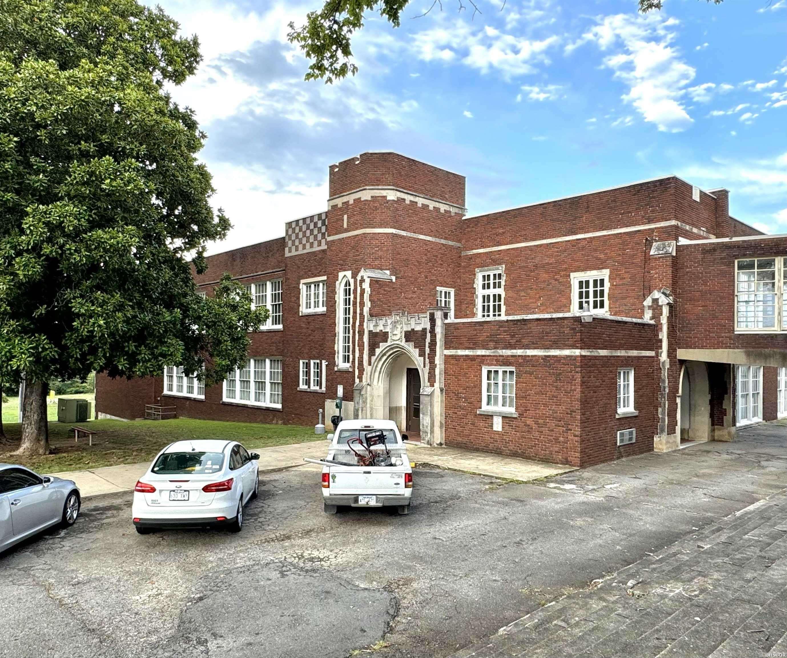 Built in 1925, the former Hot Springs High School annex building is part of Hot Springs' history. Famous for being the school attended by former President Bill Clinton, the building has been converted into 38 loft-style apartments, offering a variety of charming, well-designed units consisting of four 2BR/1BA units, four 1BR/1BA units and thirty loft-style units. Currently 37 of the 38 units are occupied, providing immediate rental income, while one unit is undergoing repairs and will soon be ready for a new tenant. A portion of the old gymnasium has been transformed into apartments, with ample space to add up to 8 smaller apartments or 4 larger apartments. Alternatively, the gym could be repurposed as a recreation area for tenants. The building features a shared on-site laundry facility and a fire suppression system for added safety. The building is commercially zoned and given its prime location near downtown Hot Springs, these apartments would also make excellent short-term rentals. The property offers on-site parking, supplemented by an additional parking lot across the street which is included in the sale. Historic tax credits may be available for improvements.