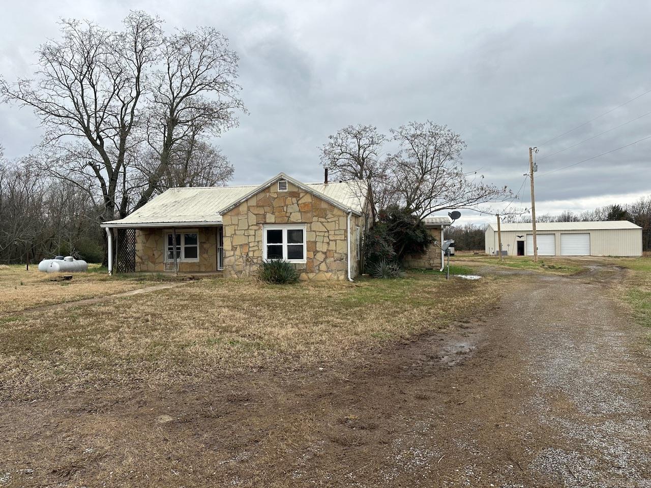 1400 Thida Road in Bradford, AR has 3.86 acres with a large shop and rock home that is in need of a complete remodel. The home is a 3 bed, 1 bath home with 1,620 square feet. The 30x60 shop has plenty of room for storing large equipment and vehicles, has a bathroom and electricity and one automatic garage door. The property has city water and is on a septic system.