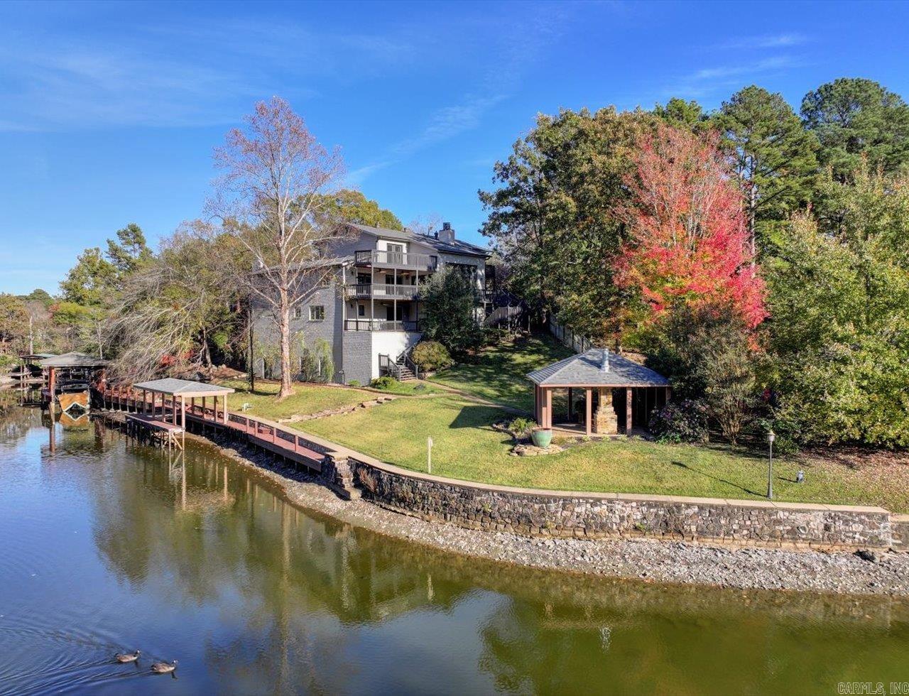 Lake Hamilton with Boat Dock! Welcome to this beautifully renovated 5 bedroom, 4.5 bath home on Lake Hamilton, offering the ultimate in lakeside living. The expansive, open-concept kitchen is a cook's dream, complete with a wet bar and seamlessly flowing into the dining and living areas - showcasing breathtaking lake views. An ideal space for entertaining family and friends. The lower level features a spacious game room, an additional living room, and a second full kitchen. Whether hosting large groups or enjoying quiet moments, this home accommodates it all. Step outside to the covered deck, where you can savor stunning lake vistas year-round. Just off your private boat dock, you'll find a cozy outdoor fireplace—ideal for relaxing with loved ones and enjoying nature, no matter the season. Retreat to your luxurious master suite, complete with direct deck access. The suite boasts a spa-like bathroom with a walk-in shower and a soaking tub—perfect for unwinding after a day on the water. This remarkable property is the perfect setting for lakeside adventures, leisure, and memories to last a lifetime. Come and see! Agents - Call Showing service to schedule all showings.