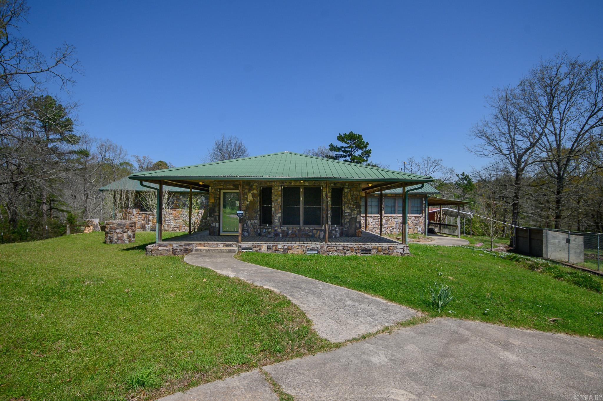 This beautiful 4/2 rock house sits on 20 sprawling acres near Lake Wilhelmina. This property boasts a plethora of amenities including an in ground pool, barn with stalls and tack room, heated dog house with enclosure, lots of storage, two garages for all of your storage needs (one can easily be converted into a separate living quarters), and two ponds perfect for fishing or lounging by. Step inside to find a cozy Sandstone wood stove, perfect for those chilly nights. Enjoy endless sunsets from the covered back deck overlooking the picturesque landscape. With no restrictions, the possibilities are endless for this truly unique property.