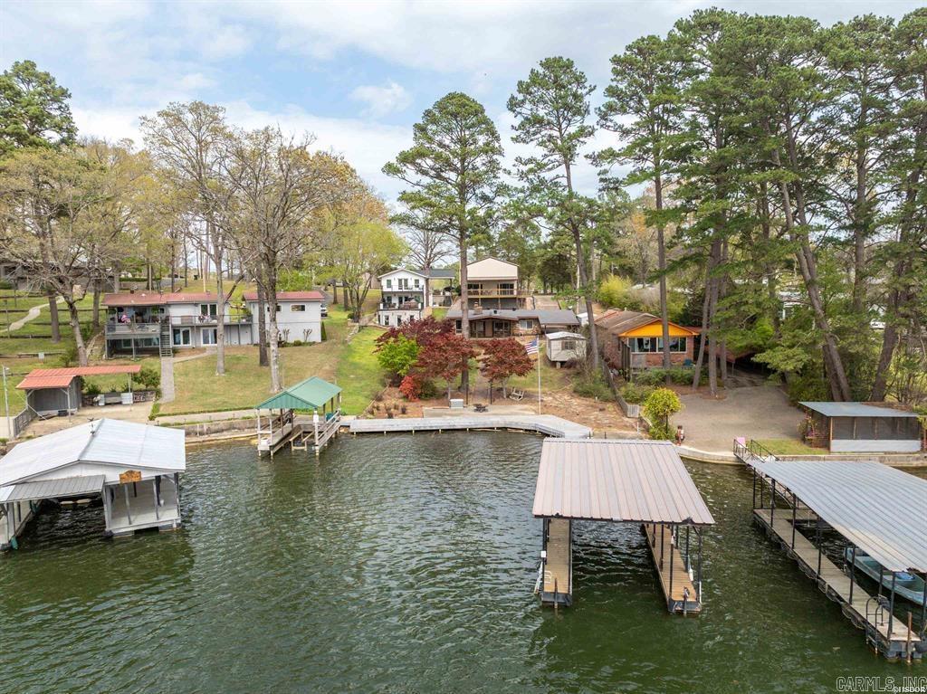 Discover this charming one-level brick lakefront home, perfect as a cozy weekend retreat, a lucrative Airbnb, or a serene full-time residence. Boasting three bedrooms and one and a half baths, this cozy gem offers both comfort and convenience. Enjoy breathtaking lake views and effortless water access with your very own floating covered boat slip, boardwalk, and lakeside patio—ideal for fishing, boating, or simply unwinding. Recent updates include new energy-efficient windows, a sleek patio door, and modern appliances. Climate control is a breeze with central HVAC and an additional mini-split system, ensuring year-round comfort. Gather around the inviting brick fireplace with gas logs for cozy evenings. Step outside onto the expansive covered deck, perfect for entertaining or simply soaking in the tranquil lakeside ambiance. The property also features a detached 30' x 42' two-car RV or storage building with impressive 16-foot high walls, two oversized 14' x 12' overhead doors, two patio doors, and its own covered deck with impressive lake views. With plans to convert the upper level into loft-style living quarters, this space is brimming with potential. Additionally, a 12' x 24' w