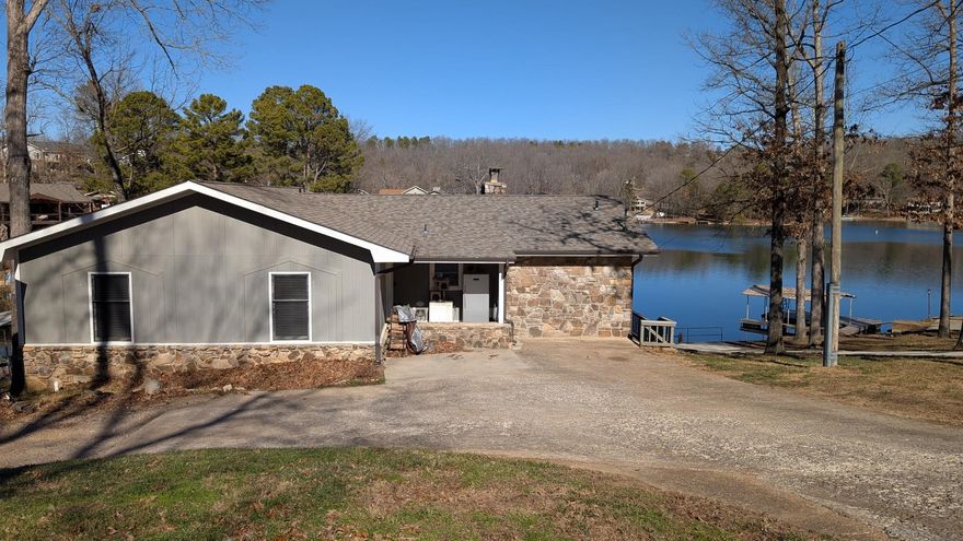 Spacious lakefront home with water views from most rooms. Features three private bedroom suites, each with its own bath and lake views. New shingles in 2023 and freshly painted throughout make this home move-in ready. Open floor plan with separate dining area is ideal for entertaining while enjoying the lake scenery. Sliding glass doors span the main level and open to the deck, with fireplaces on both the upper and lower levels. Main level updates include new cabinets, countertops, and appliances. The lower level offers a separate living area with kitchenette, bedroom, and bath, perfect for guests or extended family. All bedrooms are lake side with walkout access to upper or lower decks. Enjoy the patio above the dock, gather around a fire, or access the water directly from your private dock. Located on a quiet cul-de-sac in a protected cove with minimal boat traffic. Split floor plan with primary suite featuring double sinks and large closet. All baths have walk-in showers except the half bath. Additional storage in crawl space and shed. Circular drive provides easy access and extra parking.