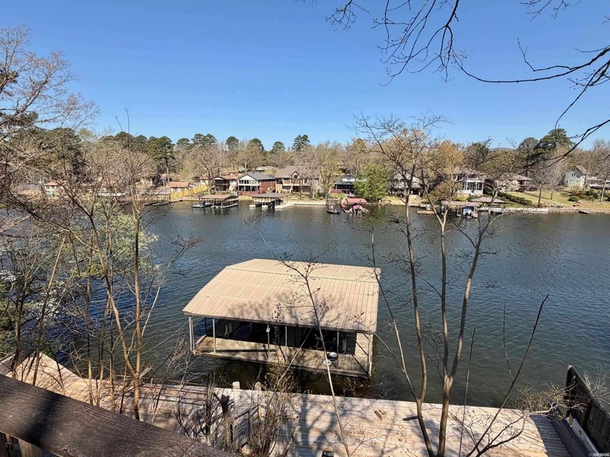 Two lake houses on one lot, right in the heart of Hot Springs. The smaller home is a throwback to the original days of the lake—a charming 1950's fishing cabin with real character, featuring original wood floors and warm interior paneling. Live in it the way it is or give it a refresh. Down below, the newer home (built in 2003) gives you a more updated lake setup. The property includes a large two-stall boat dock for easy access to the water. Live in one, rent the other. Keep both. Remodel and create something special. Lots of options with this one!