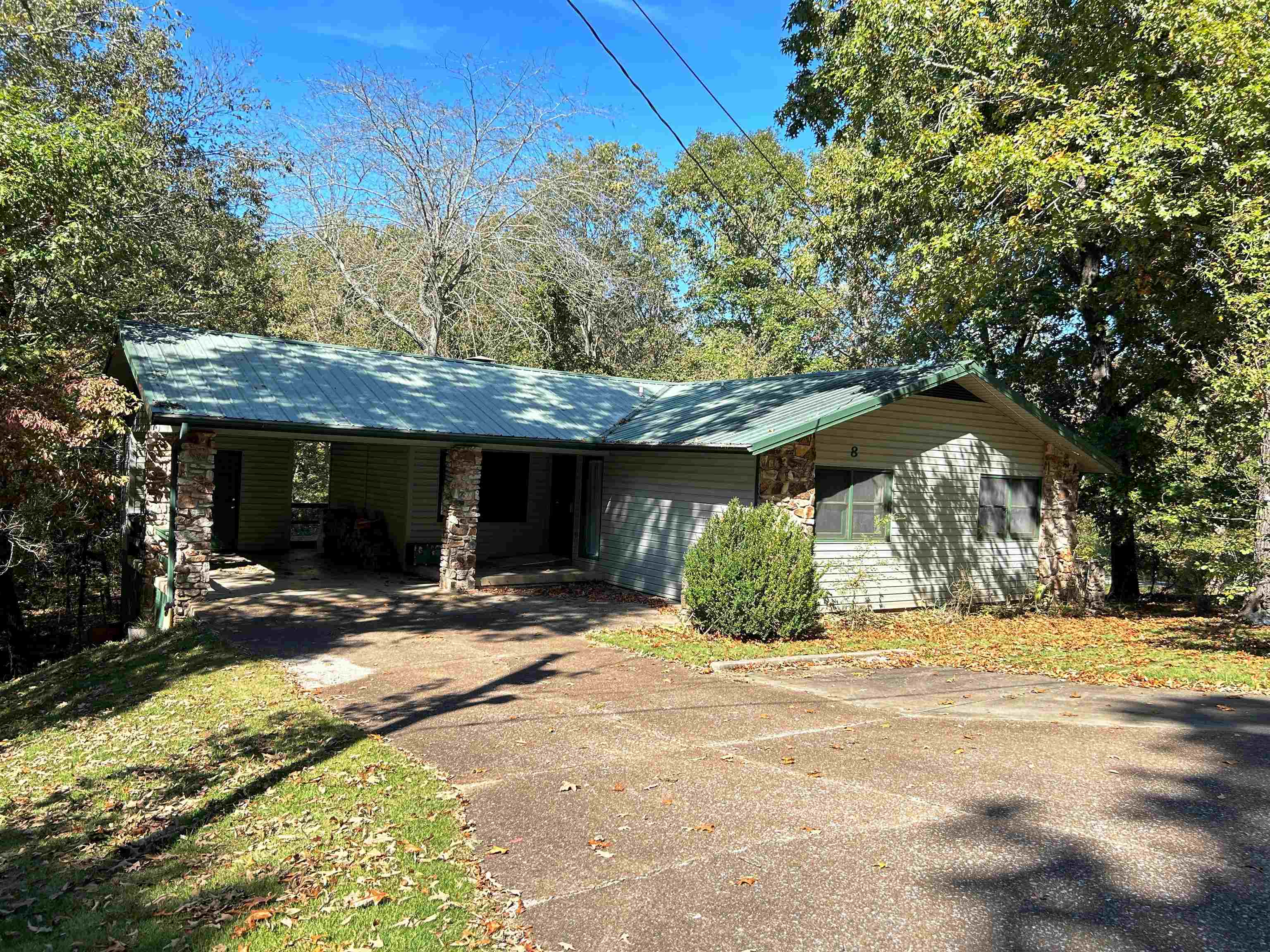 This charming ranch-style home is perfectly located near the south entrance of Cherokee Village, offering convenience and tranquility. Situated on two large, wooded lots totaling over half an acre, it’s a nature lover’s dream. Enjoy birdwatching and wildlife from the comfort of the spacious, covered back deck. The large living area features a stunning native stone wood-burning fireplace, adding warmth and character. The kitchen includes a laundry closet for added convenience, while the generously sized bedrooms provide plenty of space.  The home also offers 352 square feet of unfinished basement space, which is heated and cooled, making it ideal for a workshop or craft area and storm shelter. A large open crawl space provides easy access to plumbing, the water heater, and HVAC. The peaceful setting includes a large carport with storage and a durable metal roof.  This is a wonderful opportunity for first-time homeowners or retirees, with access to a variety of amenities, including 7 fishing lakes, two 18-hole golf courses, 2 recreation centers, and swimming pools. It’s also conveniently located near Hwy 62/412 for easy access to shopping and medical facilities.