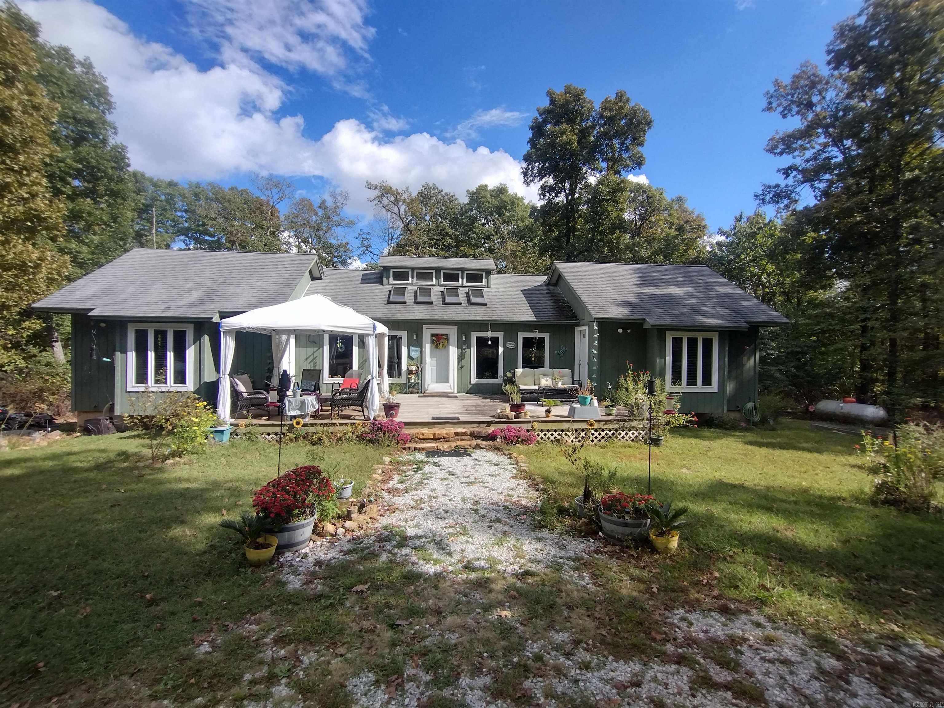 Your special place in the Ozark Mountains! Perfect vacation rental, or even your forever home. Surrounded by nature, the flowers and wildlife will make you forget you're only 15 minutes from the culture and charm of Mountain View, Arkansas. This peaceful retreat features a main house and accompanying cabin, separated by a cultivated wildflower garden, small fish pond, horseshoes and fire pit for evening gatherings. The large wooden deck off the main house is the perfect place to relax and watch the deer and turkey as the sun sets. The home generator and full basement with a safe room add more peace of mind, while the extra-large windows and skylights in the common area bring the outdoors inside in a way words can hardly express. When coming up the long driveway through the trees, this hidden escape appears suddenly, as a secret Eden revealing itself. The main house features 2 suites with showers and living/dining/kitchen common area between the two. A full unfinished basement with a walkout door gives you a clean slate to make your own vision come to life. The cabin features 1 bed and 1 bath with a kitchenette and fully screened porch, and RV Hookup