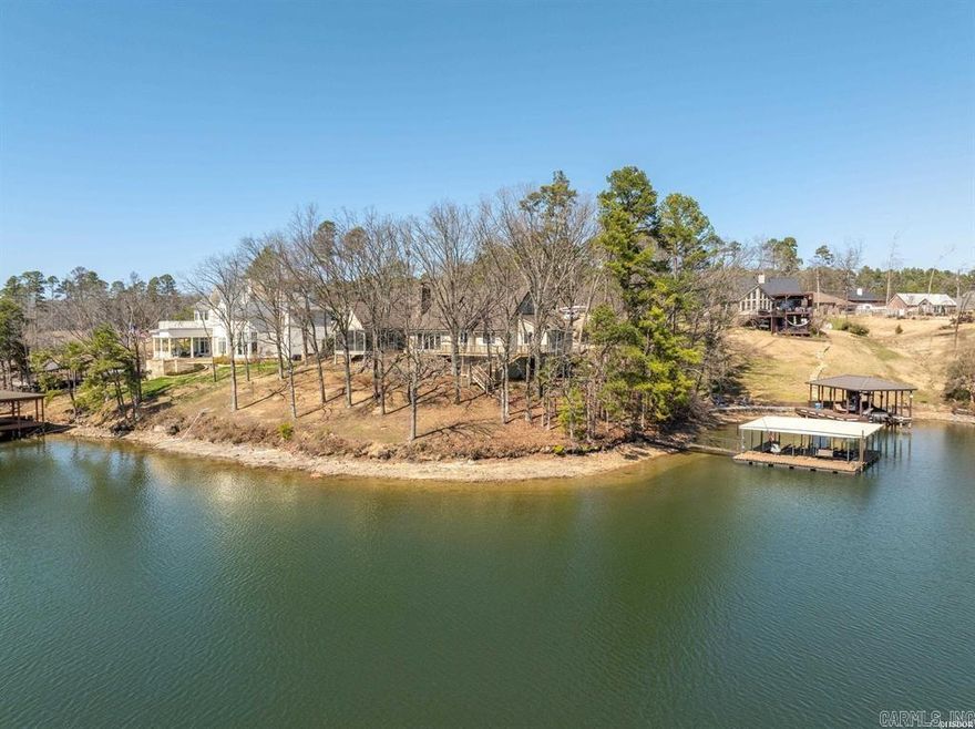 Fabulous Peninsula Drive Home sitting on the shores of beautiful Lake Hamilton with nearly 300 feet of lake front, breathtaking views, year round deep water, looking across to Garvan Woodland Gardens and Mt Riante! Abundant natural light flows through the large great room with vaulted ceiling and a beautiful natural stone wood-burning fireplace, featuring 3 beds and 3 baths, 2 on the main level... the lower level has one bed, full bath and a second living space.  The 2 stall boat dock, comes with 2 boat lifts and a swim area for all the water fun you can handle. Unwind on the large screened porch and enjoy a nice breeze while sipping your favorite beverage. The kitchen has recently been updated along with the roof which is a metal shake style. You must schedule a showing today to be ready for Lake Season 2025!