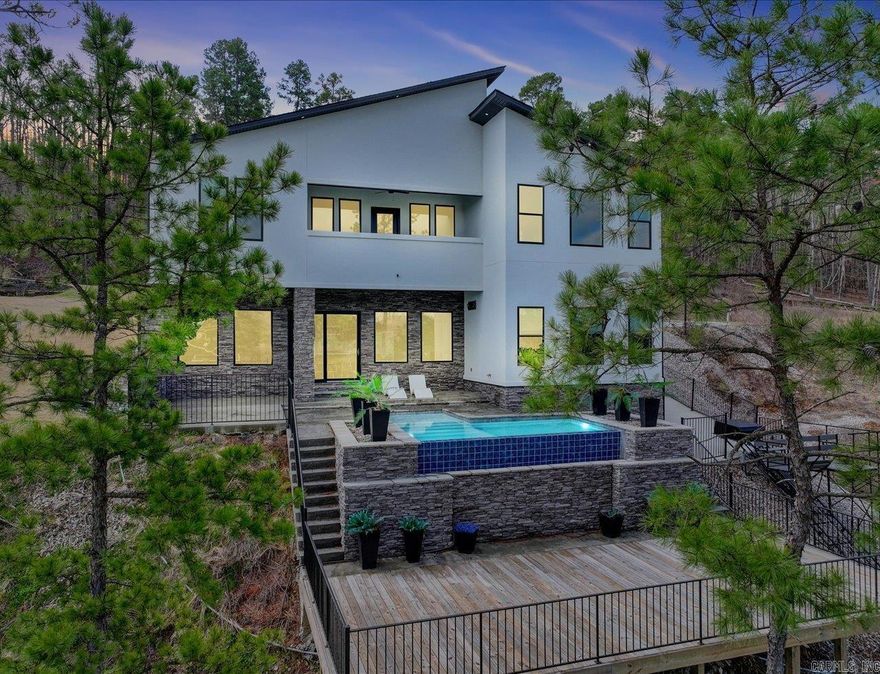 Luxury Lakefront Living on Lake Hamilton  Experience modern lakefront living on Lake Hamilton in this stunning home designed for both everyday comfort and exceptional entertaining. With 6 bedrooms, 3 full baths, 2 half baths, and 3 laundry rooms, the layout offers flexibility, space, and convenience with year-round water access and sweeping lake views.  Both levels feature full kitchens with quartz countertops, Café appliances, and thoughtful finishes—ideal for multi-level living or hosting guests. An on-demand generator provides added peace of mind, ensuring uninterrupted comfort year-round.  The outdoor living space creates a true private retreat, highlighted by a gunite infinity pool overlooking the lake. A single-bay boat dock with trolley system offers easy access for boating, fishing, and enjoying Lake Hamilton’s active lifestyle.  Inside, expansive windows fill the home with natural light and panoramic water views, while multiple living areas provide room to gather, relax, or entertain. Combining luxury, convenience, and a serene waterfront setting, this property offers a rare opportunity on Lake Hamilton.