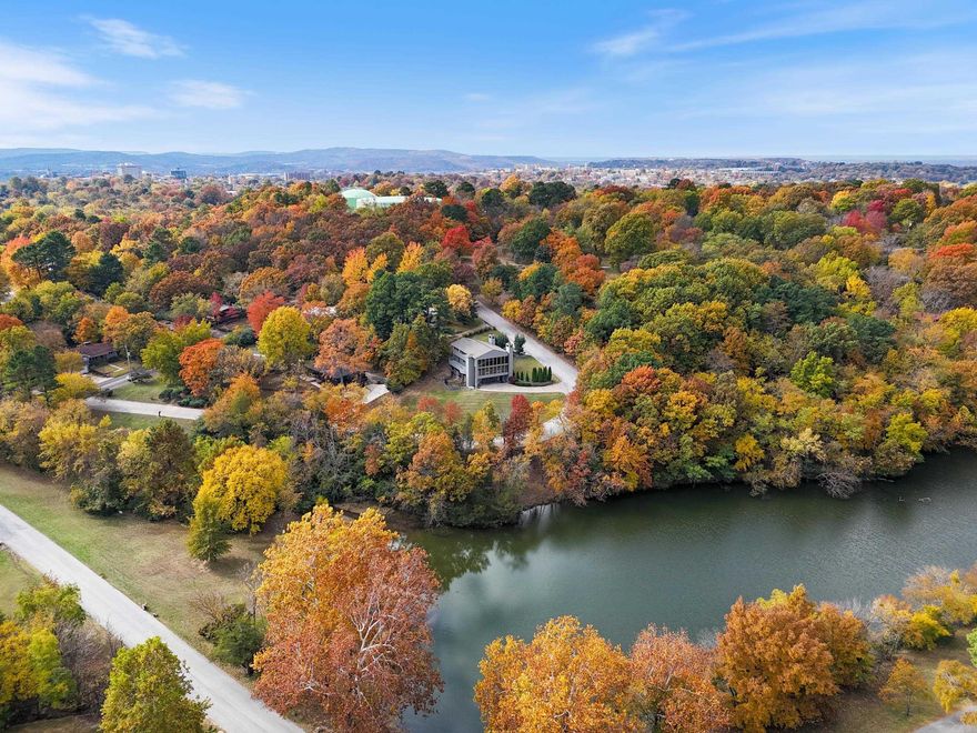 *Public Open House 12/07, 2-4PM!* Discover the final residential design by renowned solar architect James Lambeth—a unique, welcoming home on a peaceful half-acre overlooking Lake Lucille in downtown Fayetteville. Inside are four comfortable bedrooms and two and a half well-finished baths. A spacious family room connects to a flexible game/media room—currently climate-controlled for use as a garage—with a built-in entertainment center.  Features include a low maintenance private three-story elevator, newer roof, new windows, soft-water filtration, an underground electric pet fence, and a convenient laundry chute. A second-story deck with street-level access expands your outdoor living, and a home warranty adds peace of mind.  The chef-friendly kitchen centers around a modern bar, while the living room showcases a dramatic travertine fireplace and a 17-foot wall of windows with lake views. A spiral staircase, built-in media center, and cozy wood-burning fireplace add charm.  The primary suite offers a relaxing retreat with a marble bath, freestanding tub, fireplace, and double shower. A one-of-a-kind home ready for its next chapter—come see it for yourself! Schedule a showing today!