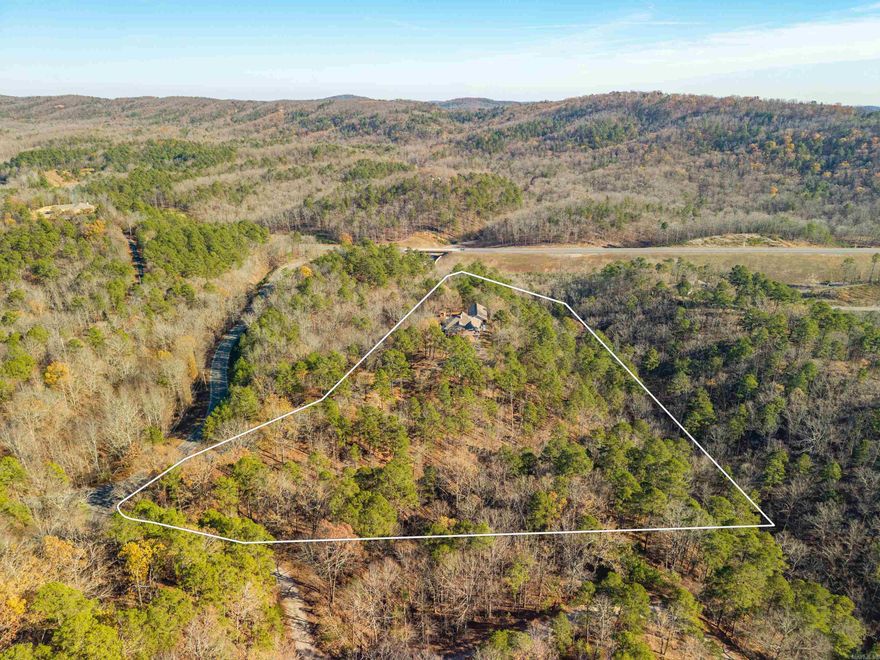 A once-in-a-generation opportunity in the heart of Hot Springs, this exceptional 8.89-acre wooded estate offers unmatched privacy, scale, and versatility. With 4,854 sq ft, it’s ideal as a private family retreat, high-performing Airbnb, or turn-key specialty business. Built in 2002 with a professionally designed annex added in 2010, the property blends comfort with income potential. The main home features 3 bedrooms, 2 full baths, light-filled living and dining areas, an open kitchen with ample storage, and a new roof (2024). The annex—currently operating as a successful Airbnb and formerly licensed for elder care—includes three private suites with dressing areas and terrace access, 2.5 baths, shared living space, accessibility features, and a finished basement for storage or expansion. Surrounded by nearly nine acres of peaceful forest with ample parking and total seclusion—yet minutes from Magic Springs, Oaklawn, Off-Road Park, and Hot Springs National Park—this is a truly rare, irreplaceable property.