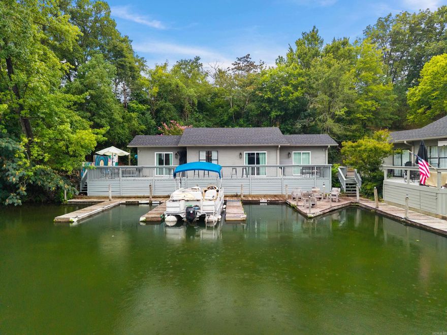 You can’t get closer to the water than this! Follow the drive down the hill to uncover this hidden gem—a peaceful cottage tucked away as the perfect lakefront retreat. This one-level townhome is located directly on the water, with a personal boat slip just steps from the back door. Cast your line or feed the fish right off the expansive back deck, perfect for entertaining friends and soaking up the sunshine. Inside, the home features an airy, open floor plan with 2 bedrooms and 2 baths, stainless appliances, and abundant natural light throughout. Fully furnished and fully equipped, this is truly a turnkey opportunity; and the property is located outside of city limits, allowing nightly rentals with no permit required. Ample parking, privacy, low POA dues, and a quiet cove location just off the main channel make this an ideal lake retreat or investment property.