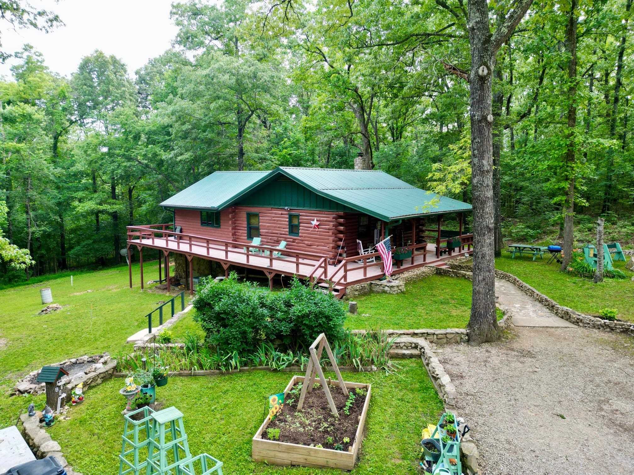 Nestled in the woods is a beautifully maintained & landscaped 2 level log/cedar home on 4.78 ac m/l. Come in and unpack your bags to start living the country life. The kitchen is a cook's delight-equipped with fridge, dishwasher, range & microwave. Oak cabinets feature pull-out shelves & pantry. The center island seats 4 and there is a sideboard for more counter and seating. Walls & ceilings are mostly log, pine T&G; flooring is wood, hickory & tile. Numerous windows allow for a bright and cheery home. The main level has a large dining room, bath and large bedroom. The lower level—with inside and outside access— can easily be a second living area. The bathroom has an oversized custom walk-in shower. Both bedrooms can handle a king-sized bed with ease and both have large closets. There is a separate laundry with washer & dryer, storage closets and mud room. Central HVAC. Other features: Metal roof, loft, 360 degree wrap around deck, Thermopane windows and sliding glass doors. 12x24 storage building. Ample parking for multiple vehicles. Fiber Optic internet (NEXT). City water. Sale includes an amenity lot in Cherokee Village which includes access to seven lakes & two golf courses.