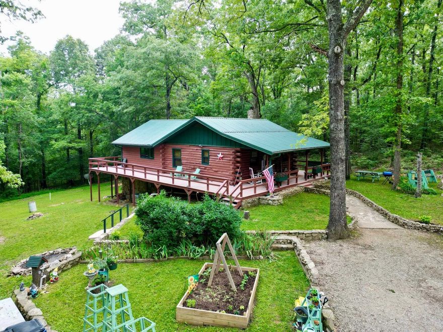 Nestled in the woods is a beautifully maintained & landscaped 2 level log/cedar home on 4.78 ac m/l. Come in and unpack your bags to start living the country life. The kitchen is a cook's delight-equipped with fridge, dishwasher, range & microwave. Oak cabinets feature pull-out shelves & pantry. The center island seats 4 and there is a sideboard for more counter and seating. Walls & ceilings are mostly log, pine T&G; flooring is wood, hickory & tile. Numerous windows allow for a bright and cheery home. The main level has a large dining room, bath and large bedroom. The lower level—with inside and outside access— can easily be a second living area. The bathroom has an oversized custom walk-in shower. Both bedrooms can handle a king-sized bed with ease and both have large closets. There is a separate laundry with washer & dryer, storage closets and mud room.  Central HVAC. Other features: Metal roof, loft, 360 degree wrap around deck, Thermopane windows and sliding glass doors. 12x24 storage building. Ample parking for multiple vehicles. Fiber Optic internet (NEXT). City water. Sale includes an amenity lot in Cherokee Village which includes access to seven lakes & two golf courses.