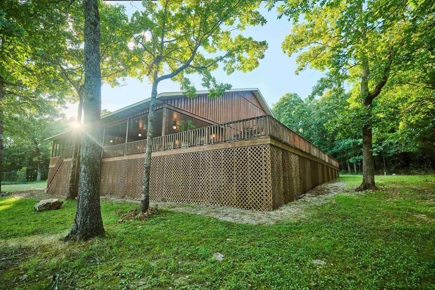 Ozark Mountain Lodge w/Breathtaking VISTA VIEWS overlooking mountains, valleys & lakes -There is a wrap around covered deck, ideal for entertaining or relaxing!! This unique Home boast 17 wooded acres+/-,& is a well kept secret nestled in the woods. This property is a outdoors person's paradise!  The main lodge features a soaring vaulted ceiling, open floor plan w/ custom oak kitchen cabinets w/wine cabinet, built in cabinets in living room, custom window shutters & impressive stone wood fireplace! The primary en-suite has walkin closet & spa-like primary bath w/French doors to the outside screened sleeping porch. Sliding barn doors to guest rooms & another full bath. Air & security smart technology system! A generous laundry room leads to a double car garage. A short distance down the mountain you'll find a creek & small hide-a-way fort for kids to use their imagination & perfect for observing wildlife. Take a nature walk trail to the guest cottage w/all amenities. Plus BONUS 0.29+/- lot in Cherokee Village providing full access to 7 lakes, 2 golf courses rec centers, trails and more! Nearby Spring River offers challenging float trips. Truly, this is an investment grade property!