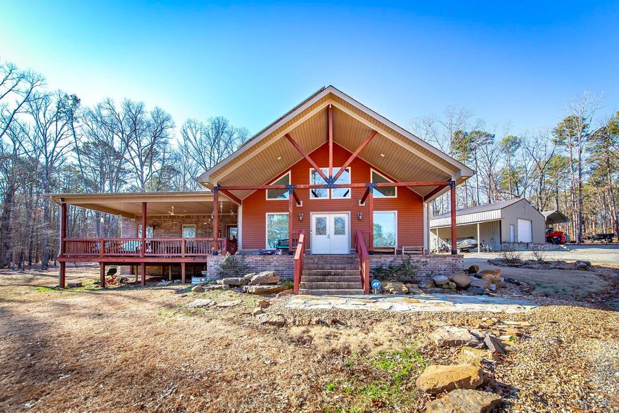Discover your dream retreat on the picturesque shores of Greers Ferry Lake. This stunning lakefront property spans 2.8 acres +/- offering the ideal blend of privacy & space, with direct access to a convenient boat ramp. Nestled next to the renowned Tannenbaum Golf Course, spend your days perfecting your swing under the sun, & your evenings basking in the vibrant hues of lakefront sunsets, or catching a wave on your boat. The expansive covered patio sets the scene for unforgettable gatherings while the serene mornings provide the perfect backdrop for a quiet coffee ritual as you watch the lake’s still waters. Inside, the open & vaulted living/dining area is bathed in natural light, courtesy of a striking wall of windows that offer uninterrupted views of the lake. This property is as efficient as it is beautiful, with solar panels providing significant energy savings. Custom trim was harvested from local trees on the land. Storage is abundant, with two carports & a spacious 30x36 insulated shop building, ideal for those cherished lake toys. The shop is roughed in for plumbing offering the opportunity for expansion to add a guest suite. Your lakeside sanctuary awaits.