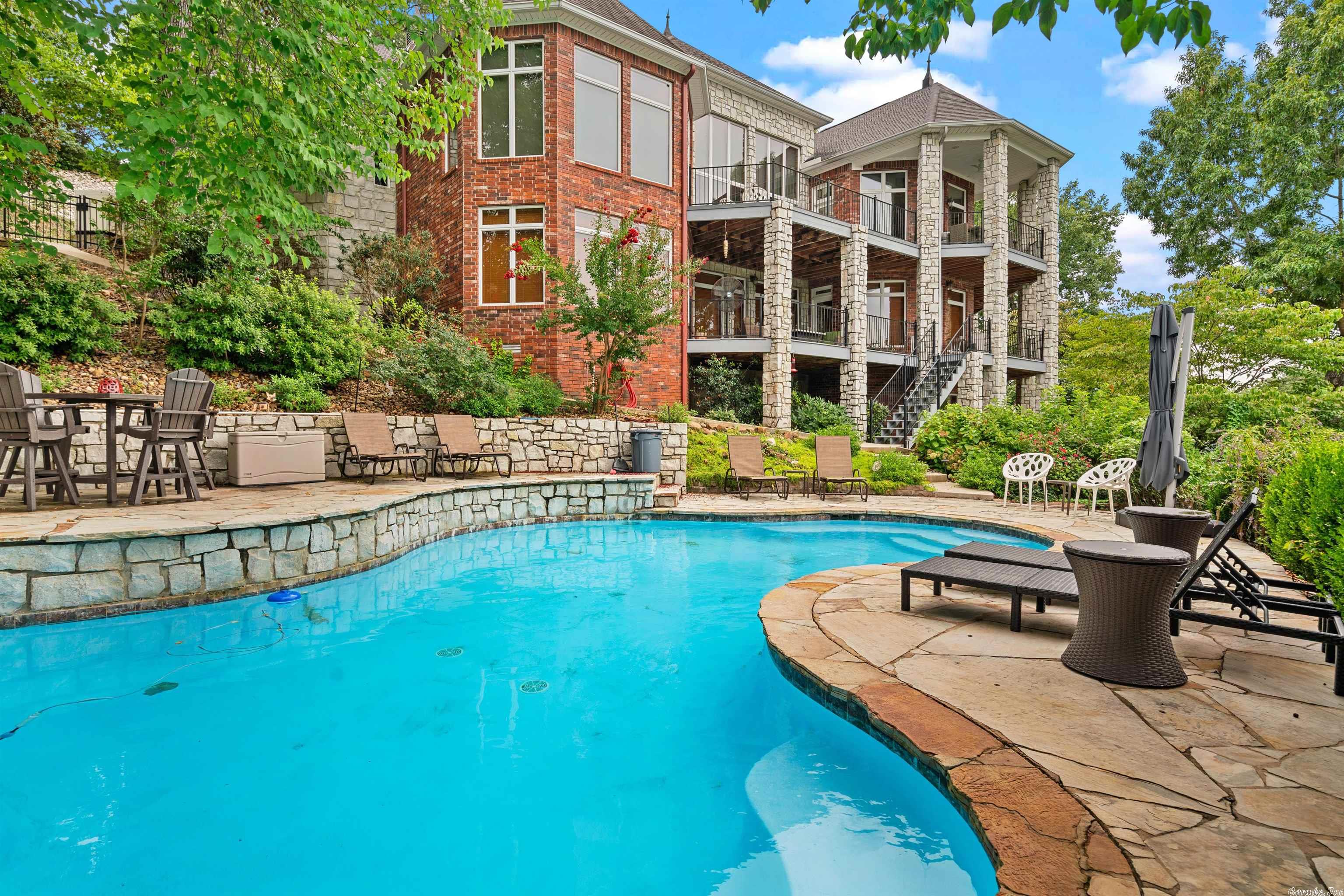 Beautiful Lake Hamilton Home with Stunning Panoramic Views! Located in gated Stonegate Shores this beauty offers everything you need for a perfect lake life. Inground pool with terrace and waterfalls, main level balconies for morning coffee & moonlight dinners, private downstairs covered balcony for guests, media room with wet bar & wine fridge, 3 car garage, his & hers office spaces, jet ski lifts, separate area for gym equipment, and oversized windows for those million dollar lake and vista views!