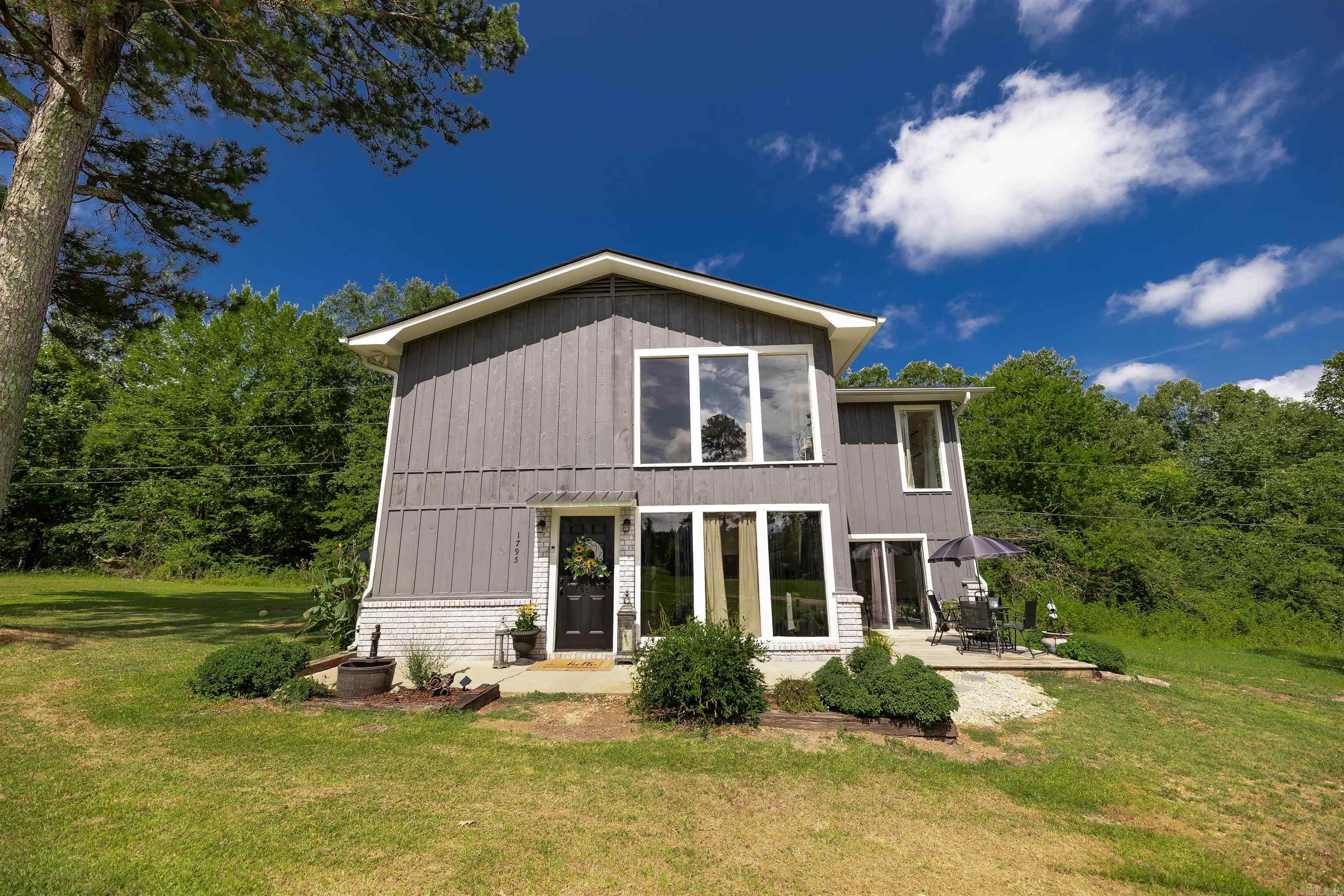 Welcome to this beautifully updated retreat tucked just off the main road, offering privacy, charm, and character in equal measure. Step inside to a stunning lofted living area filled with natural light streaming through tall windows that frame the serene surroundings. At the heart of the home is a dramatic floor-to-ceiling wood-burning fireplace, perfect for cozy evenings and a striking focal point year-round. The open-concept design flows effortlessly into a neutral, updated interiorāready to complement any style. Upstairs, youāll find a spacious en-suite bedroom and sitting room overlooking the main living area, with peaceful views and plenty of privacy. Storage is made easy with convenient outdoor storage space, and recent upgrades like a newer roof and sleek remodeled bathrooms offer peace of mind for years to come. Donāt miss this rare opportunity to own a home that balances unique personality with modern updatesāall in a quiet, accessible location.