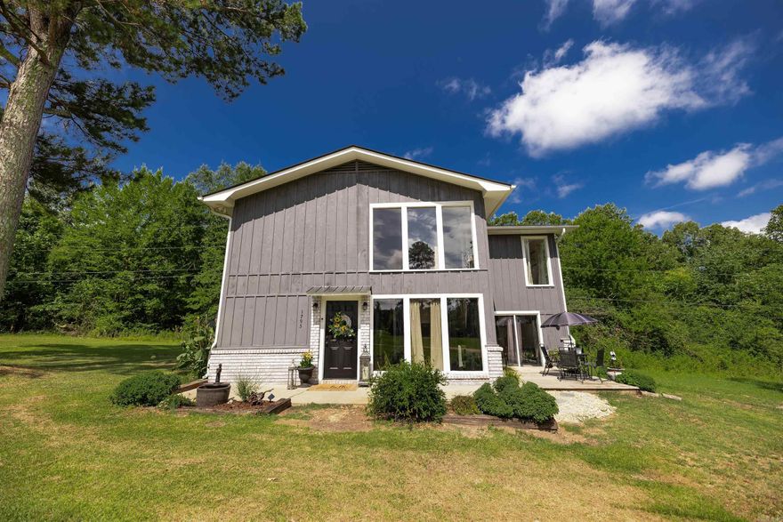 Welcome to this beautifully updated retreat tucked just off the main road, offering privacy, charm, and character in equal measure. Step inside to a stunning lofted living area filled with natural light streaming through tall windows that frame the serene surroundings.  At the heart of the home is a dramatic floor-to-ceiling wood-burning fireplace, perfect for cozy evenings and a striking focal point year-round. The open-concept design flows effortlessly into a neutral, updated interior—ready to complement any style.  Upstairs, you’ll find a spacious en-suite bedroom and sitting room overlooking the main living area, with peaceful views and plenty of privacy. Storage is made easy with convenient outdoor storage space, and recent upgrades like a newer roof and sleek remodeled bathrooms offer peace of mind for years to come.  Don’t miss this rare opportunity to own a home that balances unique personality with modern updates—all in a quiet, accessible location.