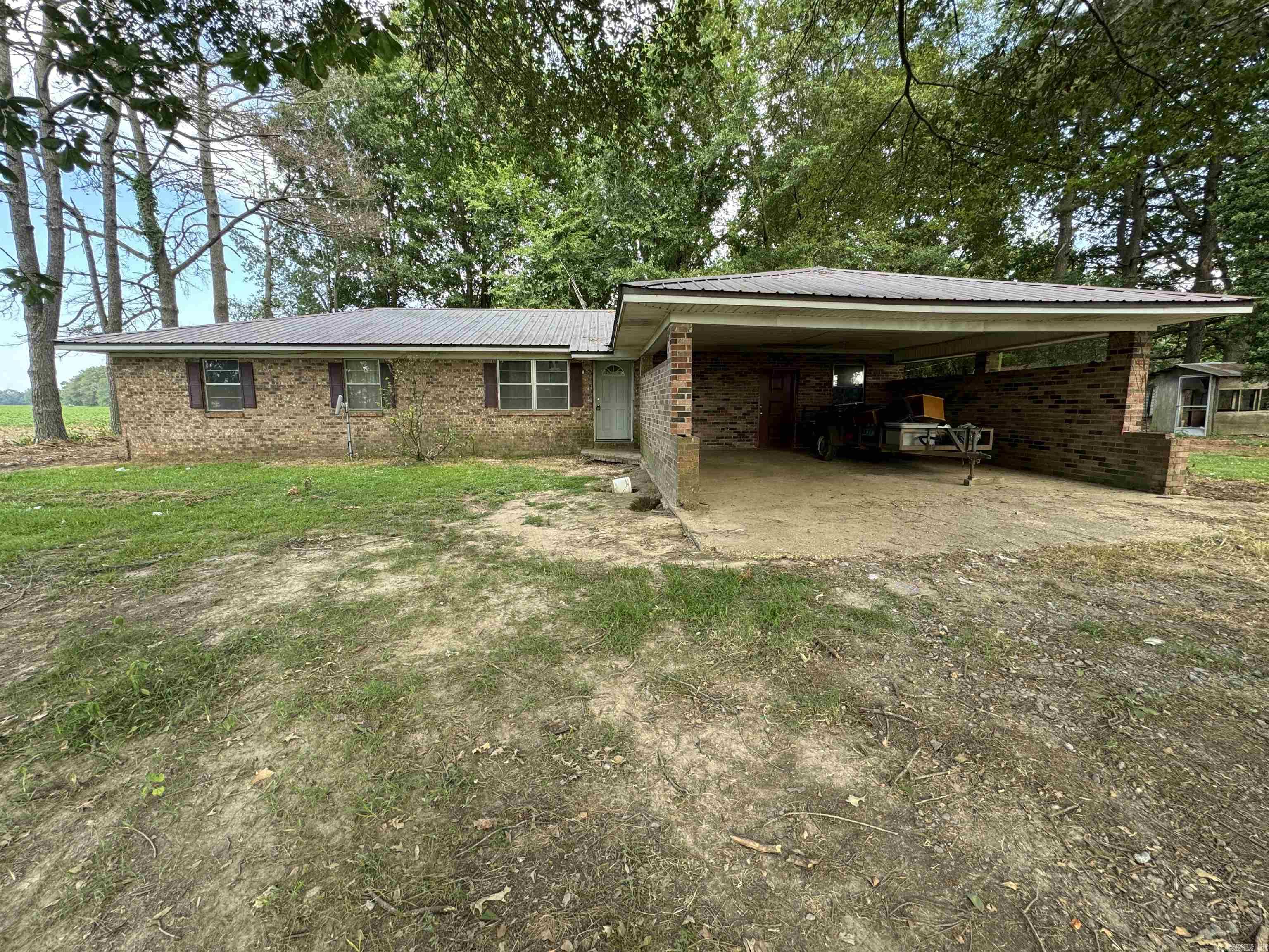 Come see the potential in this 3/2 with a living room and a den. Brick home surrounded by farm fields just off the highway. It would be a good starter home, or a fixer upper. Covered 2 car garage and sits on over an acre of land. Come check it out today.