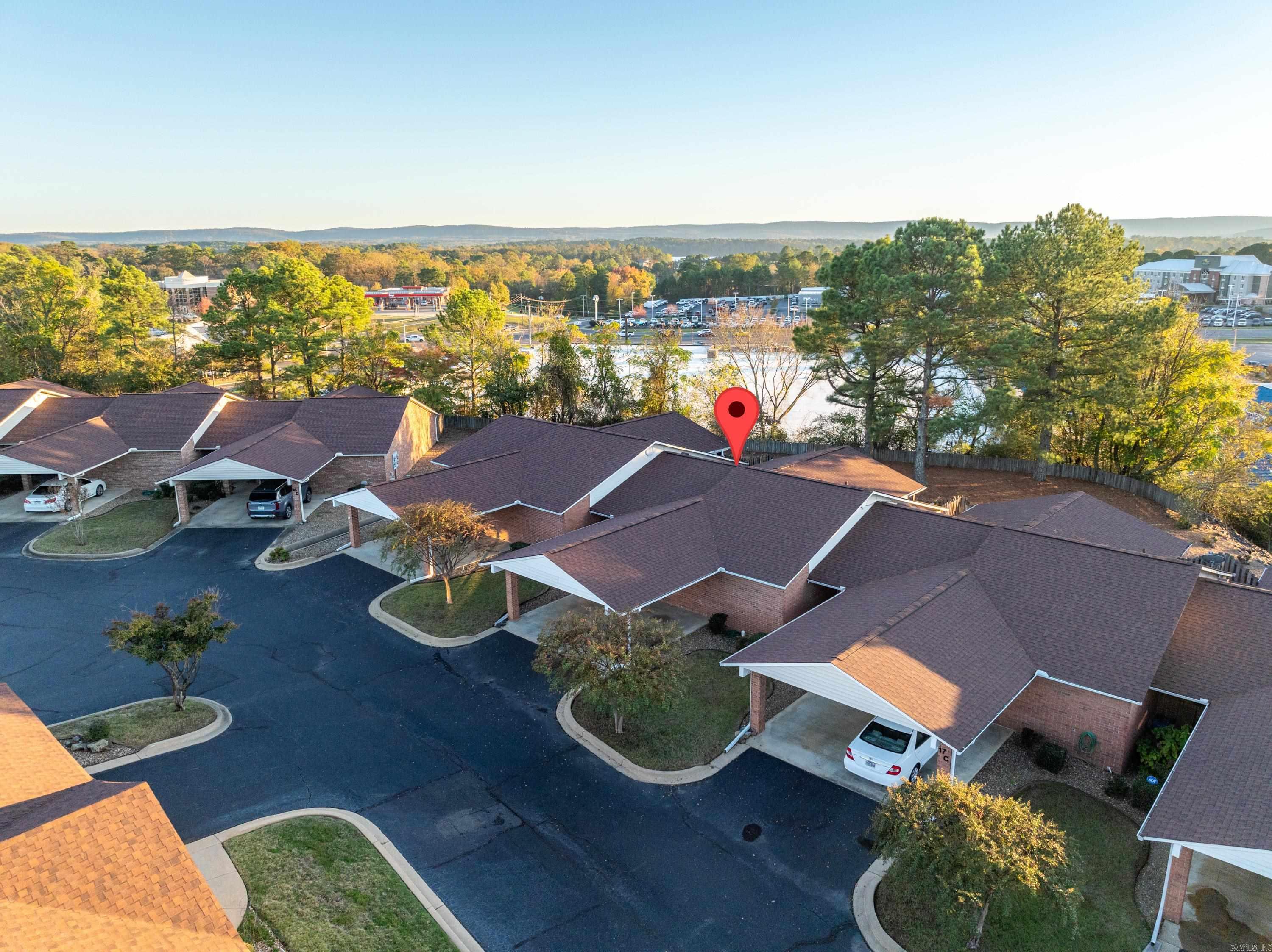 This charming 2-bedroom, 2-bathroom garden home is nestled in the desirable Heights HPR (55+ community) in Hot Springs. Set amidst beautifully landscaped grounds, the home offers a peaceful, park-like atmosphere, conveniently located near shopping, hospitals, lakes, and restaurants. This single-level unit features a 2-car attached carport that leads directly to a covered front porch. A partially screened back patio, accessible through sliding doors from both the living/dining room and primary bedroom, overlooks a fenced backyard, providing a private retreat. Additionally, there is a small attached outdoor storage/workshop with electricity. The home sits on a hill, surrounded by mature pine trees and crepe myrtles, creating a serene and secluded backyard oasis. The HOA covers exterior insurance, landscaping, water, trash, and more!