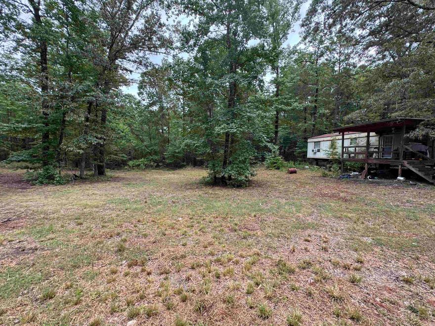 Discover 15 acres of opportunity tucked away in a private, wooded setting just 10 minutes from Walmart and the roundabout. While there is a bit of slope throughout the property, you'll also find a cleared, level section that would make a great building site for a house, cabin or mobile home. With no HOA fees and no restrictions, you'll enjoy the freedom to use the land as you choose. A well and septic tank are already present. There are 2 older mobile homes and a shop house on the property, they are in poor condition and likely best suited for removal unless you're up for a renovation project! The value here is in the land. Offered as-is for it's incredible potential. Freedom, privacy and convenience, all in one property!