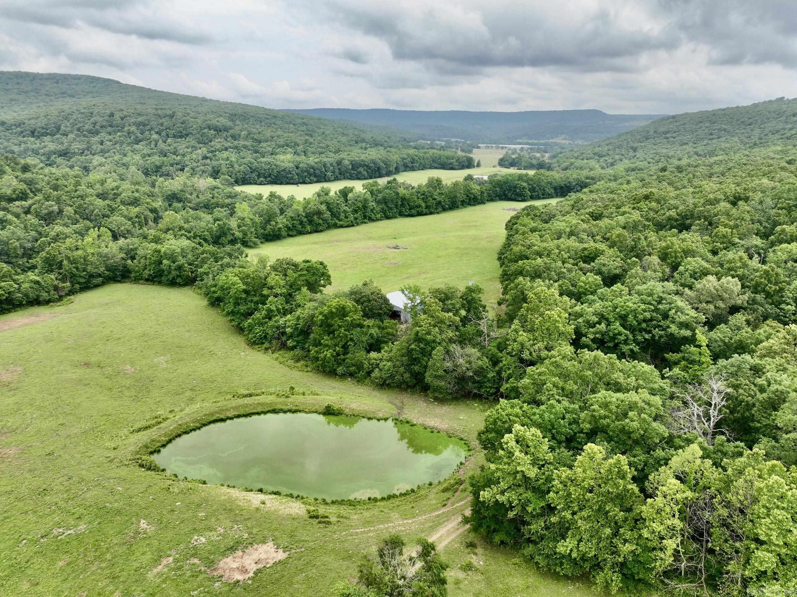 Welcome to the breathtaking cattle ranch located in the heart of the Ozarks. As you enter through the gated entrance and drive along the private road, you'll immediately notice the beauty surrounding you. The ranch boasts lush open bottom fields, perfect for cattle grazing and hay production, ensuring a thriving agricultural operation. The thoughtful design of this ranch includes two separate corrals with working pens, making livestock management a breeze. The entire property is fenced and cross-fenced, providing secure boundaries for your cattle. You'll find a well-built metal barn on the ranch, offering ample space for equipment and hay storage. With everything organized and protected, you can efficiently manage your ranching activities. One of the highlights of this property is Lollars Creek, meandering through the heart of the ranch. The tranquil sound of flowing water adds to the serene atmosphere. Additionally, multiple ponds are scattered throughout the property, offering an additional water source for livestock and creating picturesque views. The panoramic views from various points on the ranch are simply spectacular.