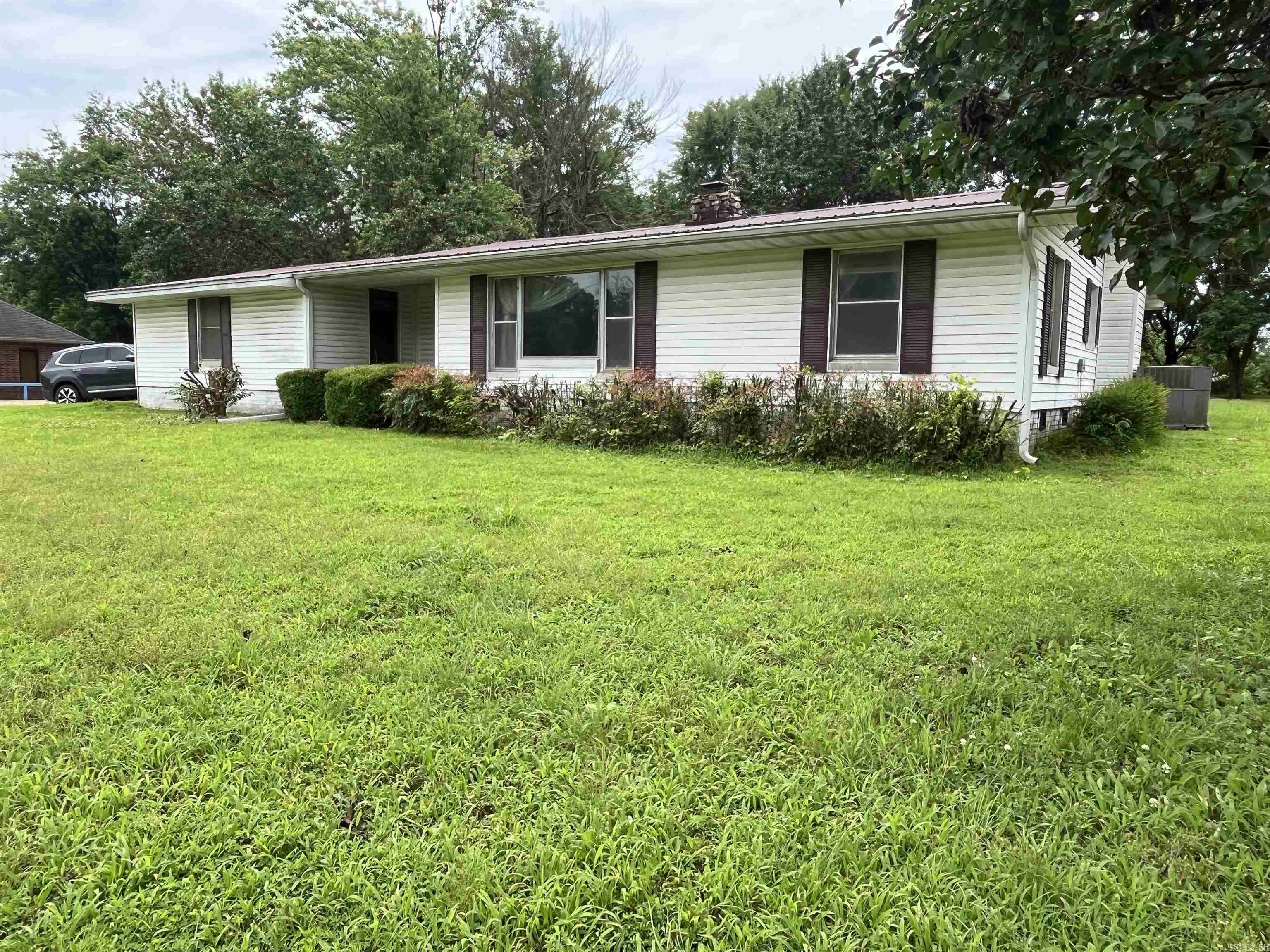 Located at the corner of North 1st Street and Tranquil Lane, this well-loved 3-bedroom, 2-bath home offers comfort, potential, and versatile living spaces. Situated on a corner lot, the home features a brick perimeter foundation, vinyl siding, and a durable metal roof. Enjoy the outdoors on the covered side porch overlooking the fenced backyardāideal for pets, play, or entertaining. A separate outdoor storage area provides convenient space for tools, equipment, or seasonal items. Inside, the home offers a functional layout with a kitchen equipped with a range/oven and dishwasher, conveniently located next to a cozy dining area. A stone fireplace with a wood-burning insert serves as the centerpiece of the spacious living room. The large primary suiteāadded after the original construction in the 1960sāincludes a bathroom and sliding glass doors that open to the backyard. Two additional bedrooms share a full bath, and a flexible bonus room off the kitchen can be used as a second living area, home office, or even a fourth bedroom. This property offers excellent potential for customization and is ideally located approximately 1.5 miles from the Caddo River and within walking distance to