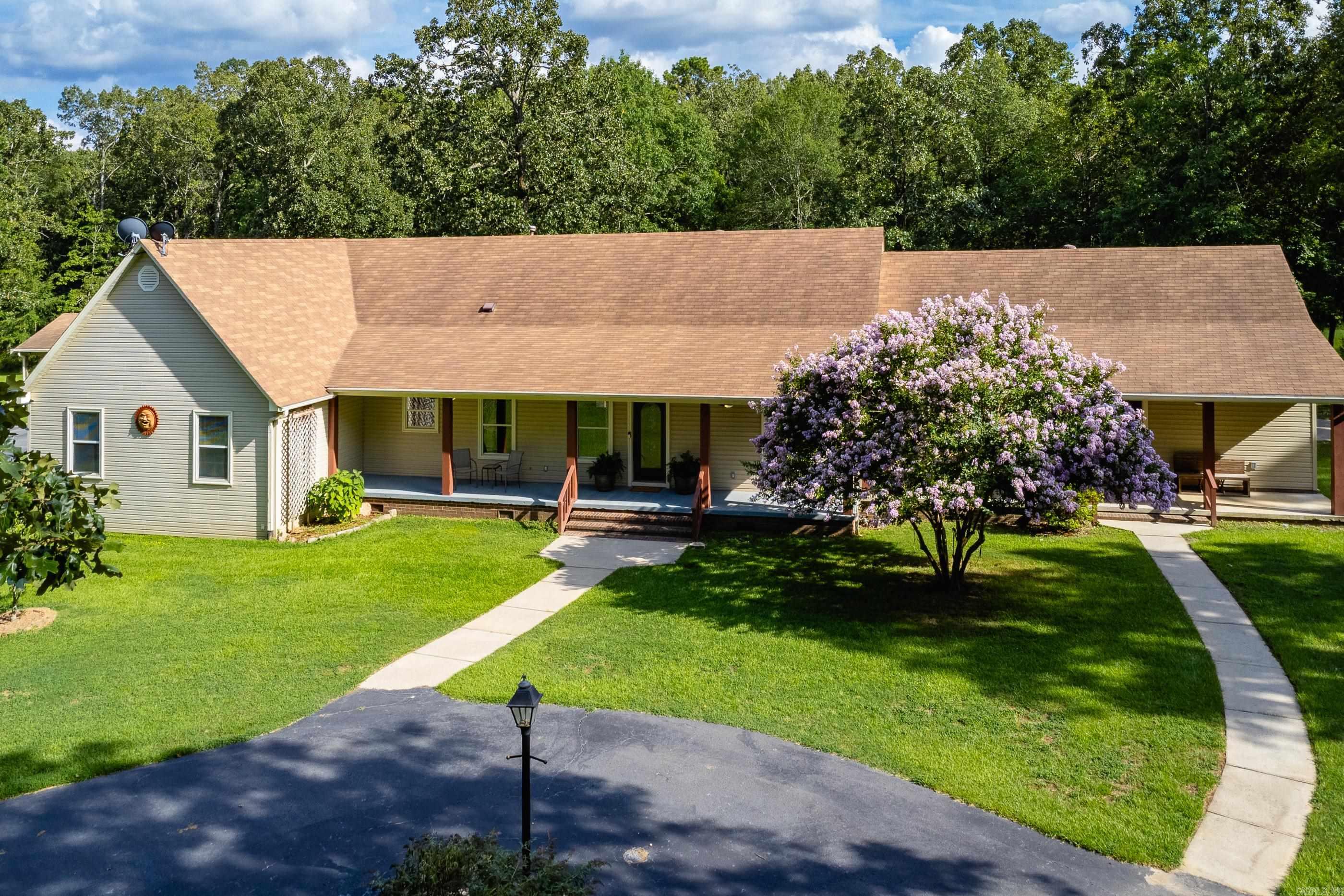 Spacious and versatile, this rural country home on nearly 5 acres offers a rare multigenerational setup ideal for extended family or guests. The main home is welcoming with a charming front porch and foyer leading into a vaulted great room with a fireplace. The large kitchen and dining area is perfect for formal and informal gathering and entertaining. Off the kitchen is the laundry as well as the primary suite including an updated bath, huge walk-in shower, walk-in closet, and a sunroom or sitting room for quiet relaxation. Two additional guest bedrooms and a full hall bath are located apart for added privacy. A separate in-law quarters is attached by a hallway and features its own front porch, living area, full kitchen, spacious bedroom and bath, laundry, and private carport, perfect for independent living. Multiple decks span the back of the home, offering peaceful views and outdoor space to enjoy the setting. Ample storage throughout, including generous closets, a two car garage on the main house, and an additional detached garage/shop with an attached carport/covered area. A unique property in a lovely setting. Come see.